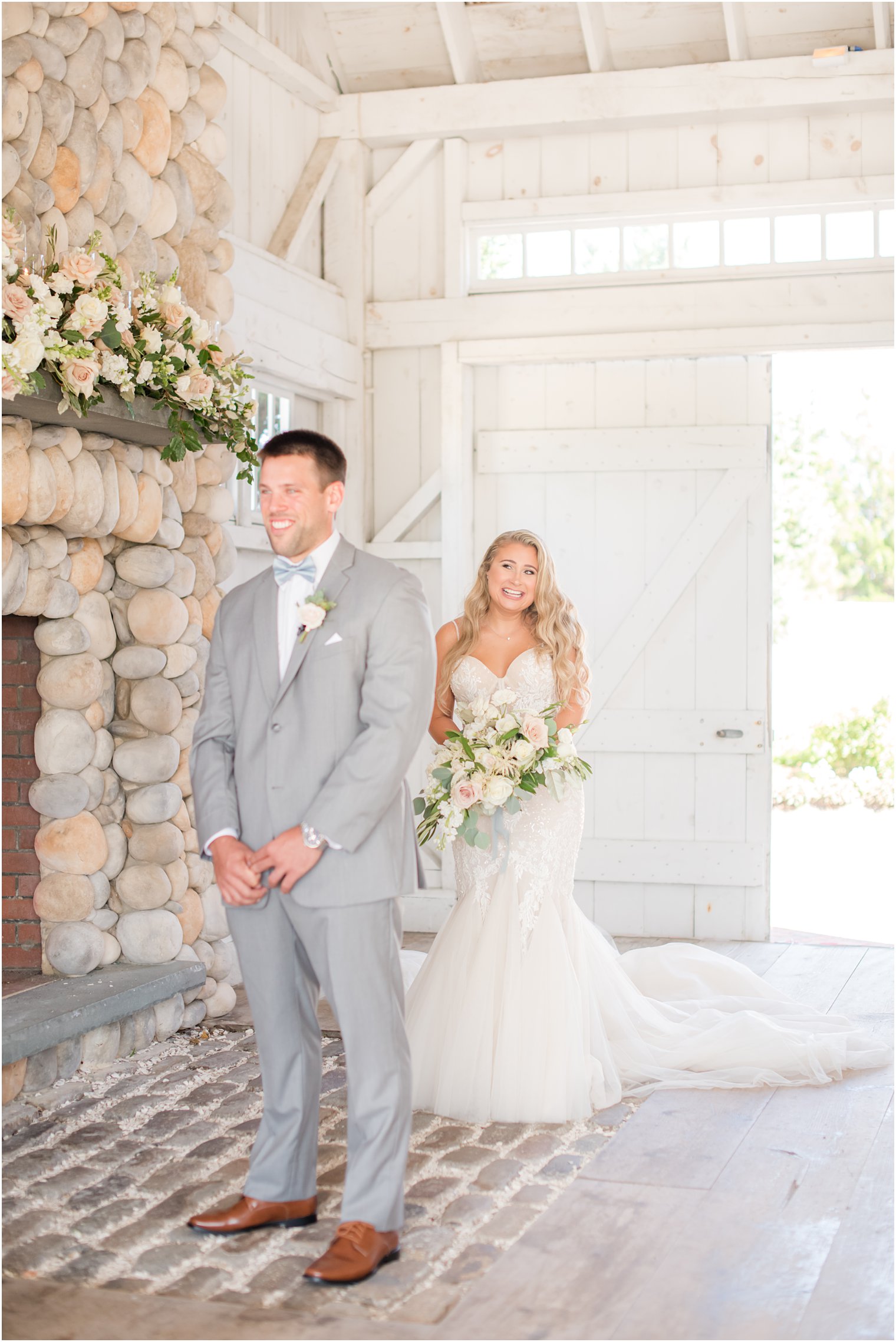 bride walks up to groom for first look in white barn of Bonnet Island Estate