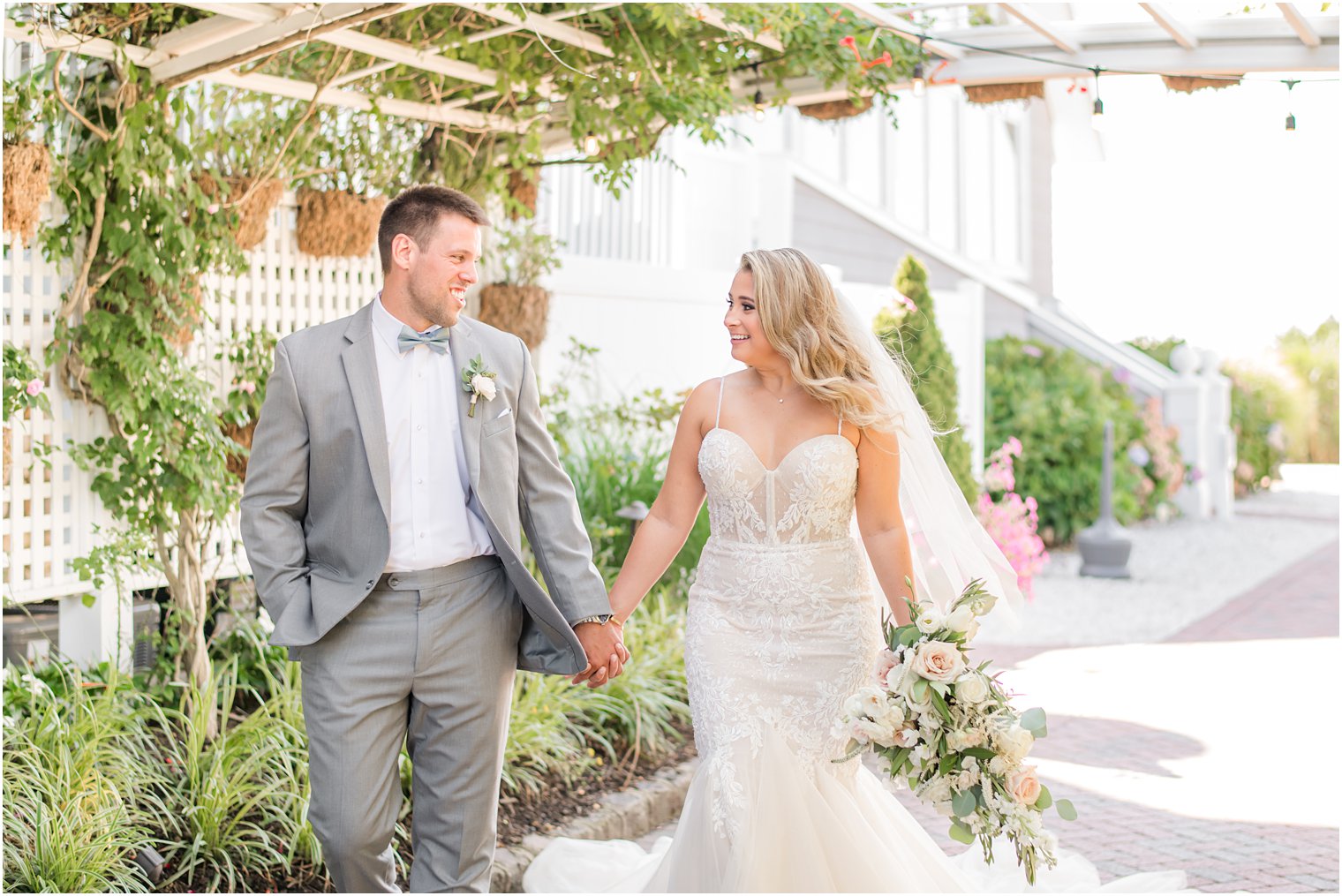 newlyweds hold hands walking through rose garden at Bonnet Island Estate