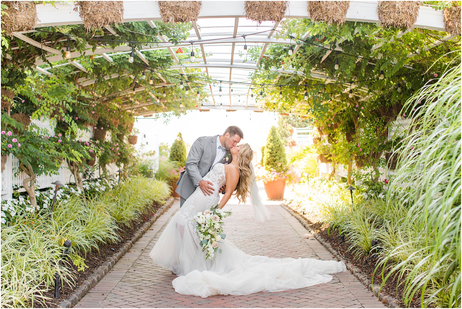 newlyweds kiss during Bonnet Island Estate wedding portraits in rose garden