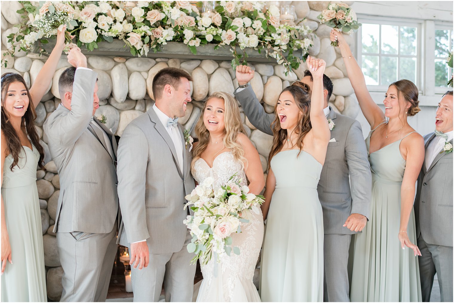 wedding party cheers while bride and groom laugh together