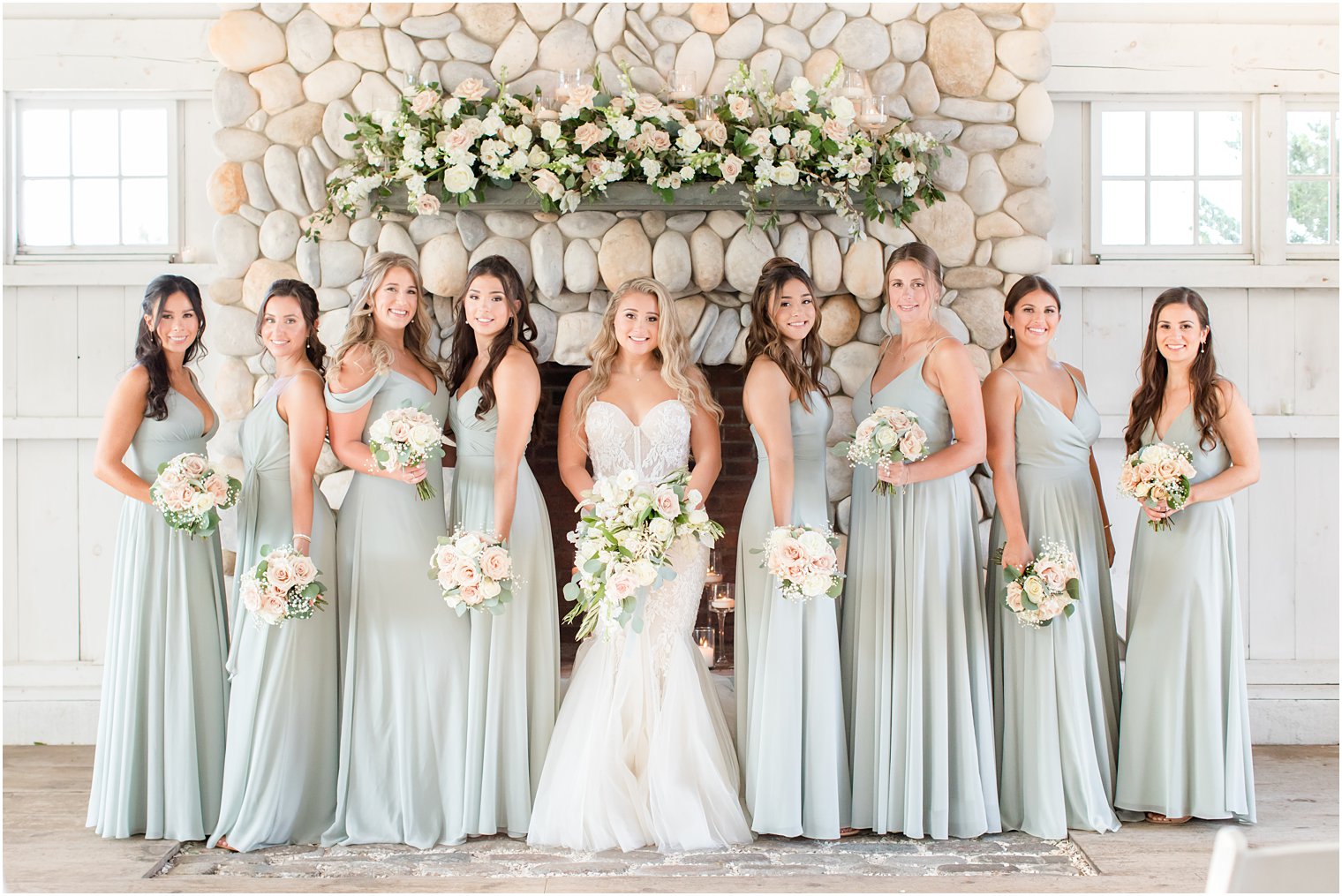bride poses with bridesmaids in mint gowns with pastel bouquets