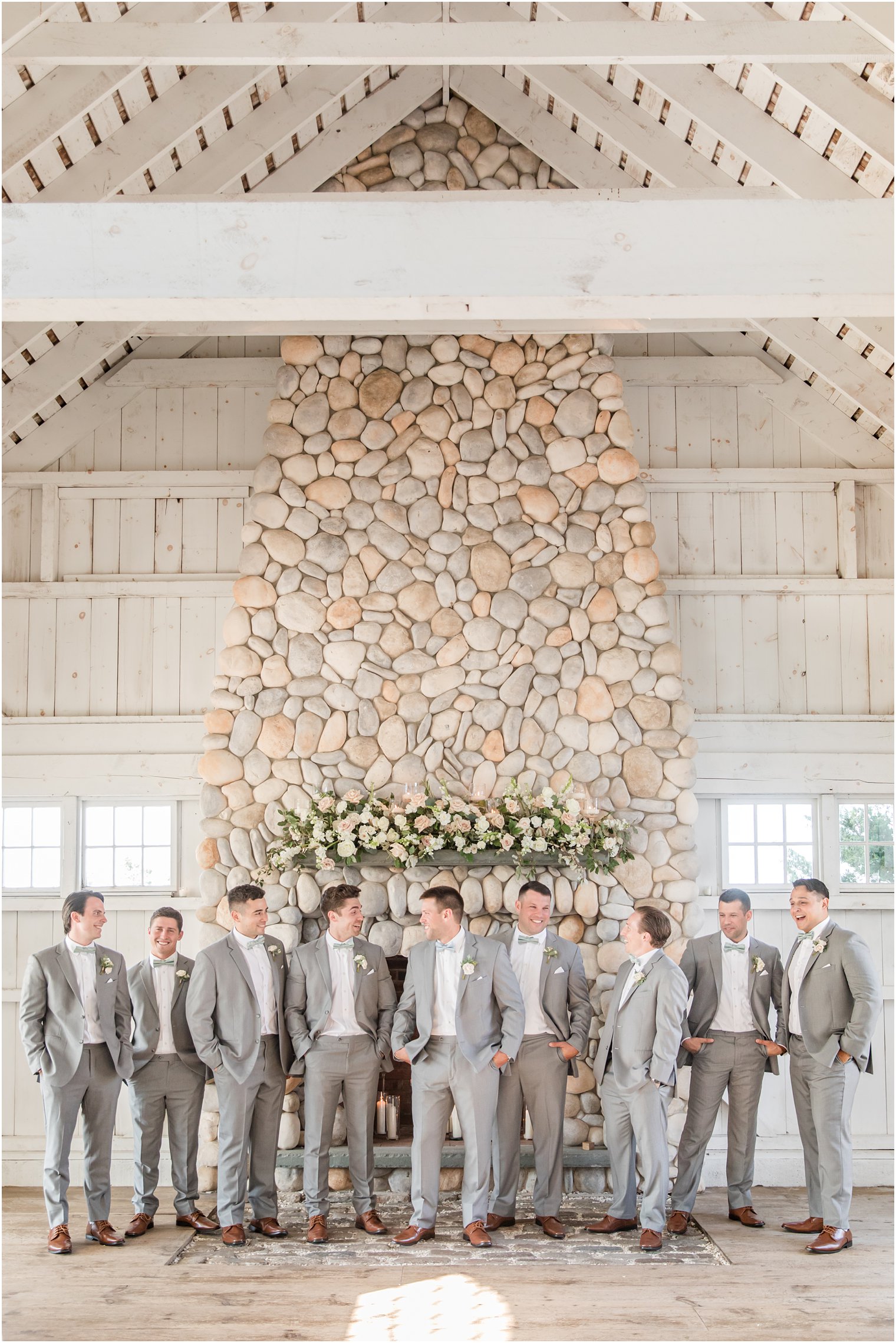 groom stand with groomsmen in grey suits by stone fireplace