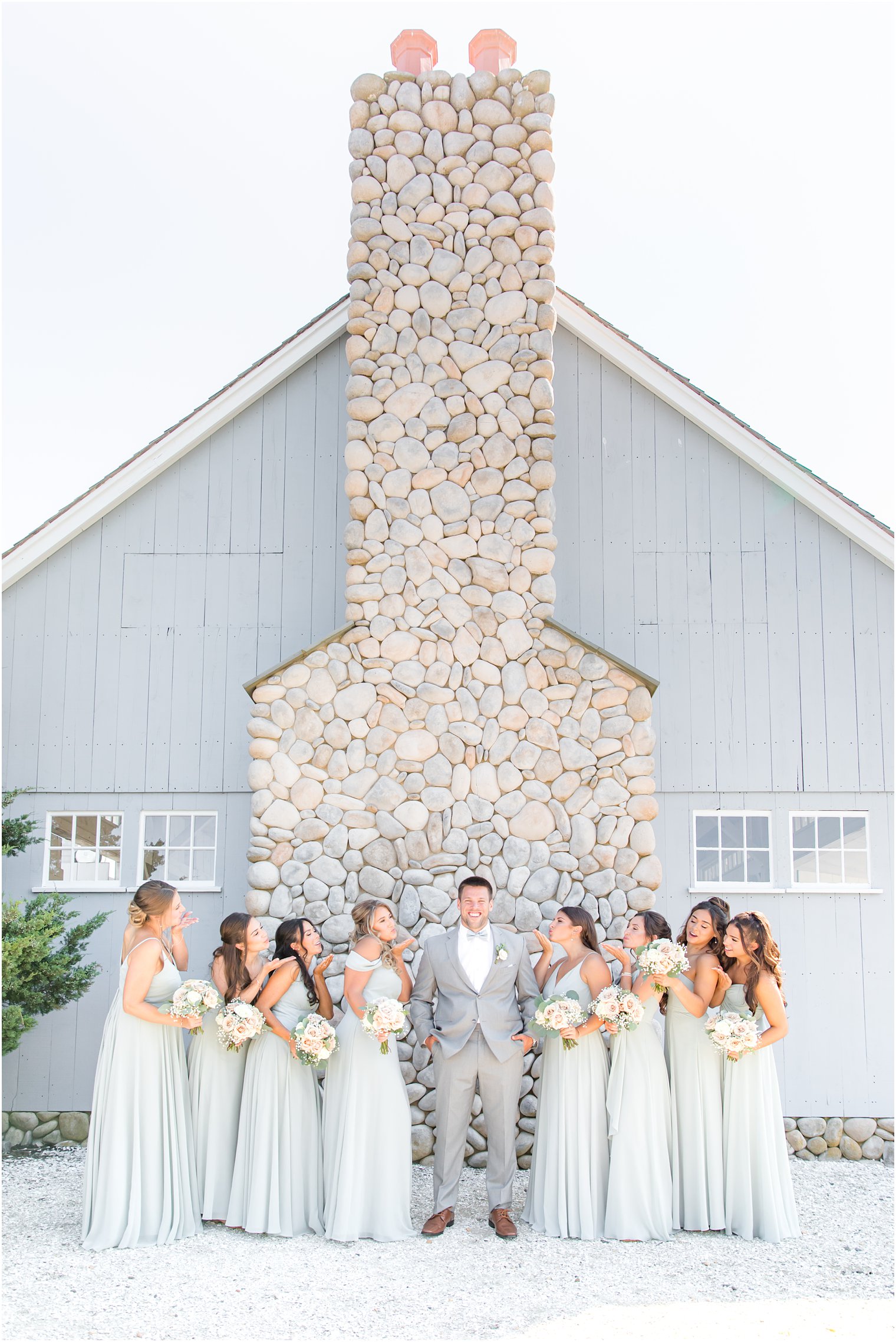 groom poses with 8 bridesmaids in mint gowns
