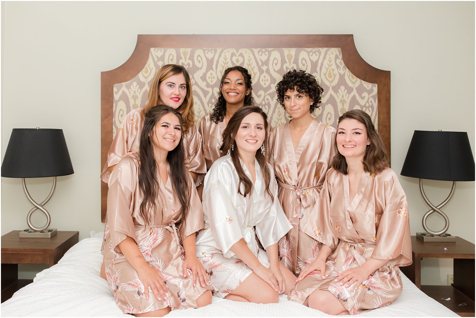bride and bridesmaids sit on bed before Chauncey Hotel wedding
