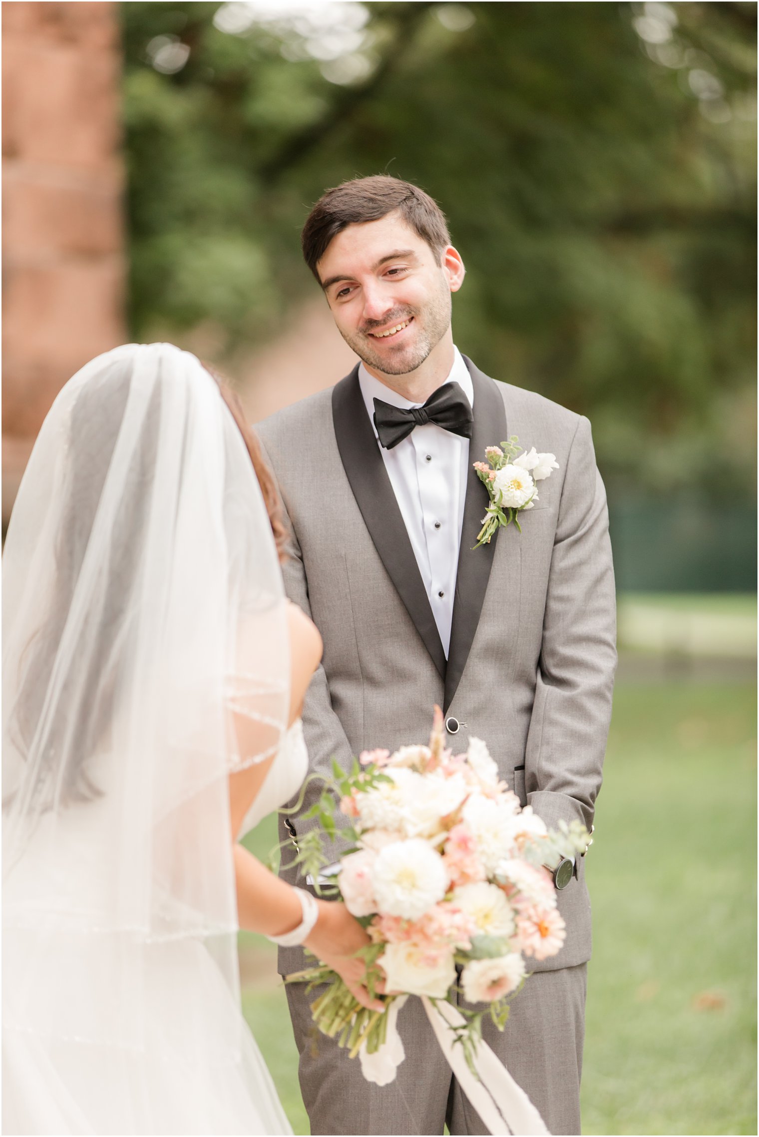 groom smiles at bride during first look in New Jersey