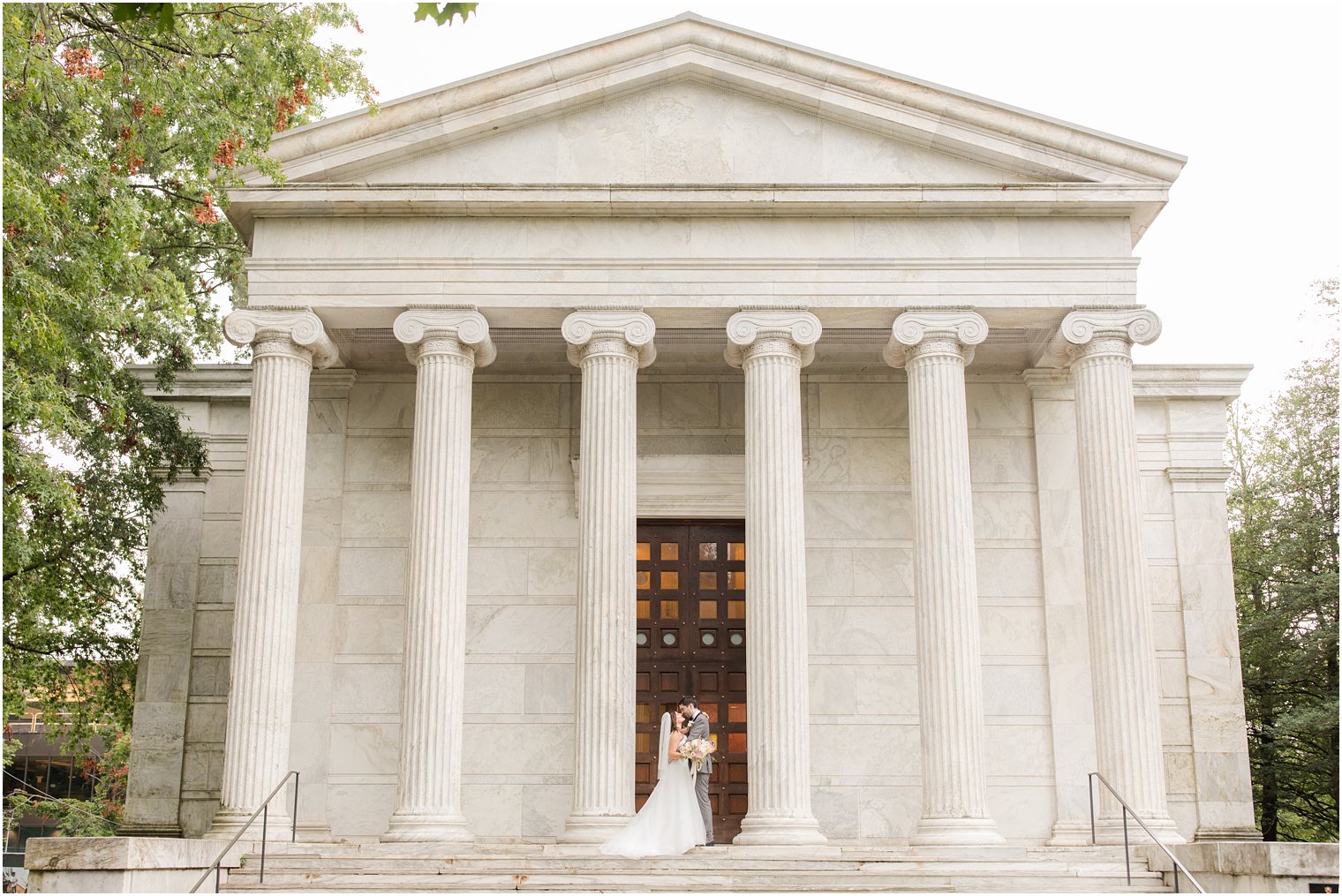 newlyweds pose on steps of building at Princeton University