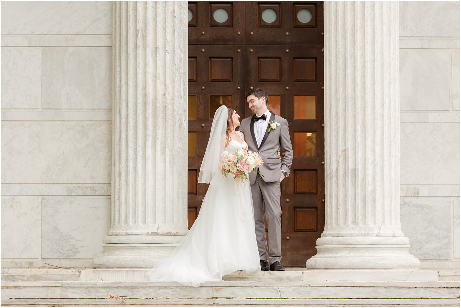 newlyweds stand on steps by wooden doors at Princeton University