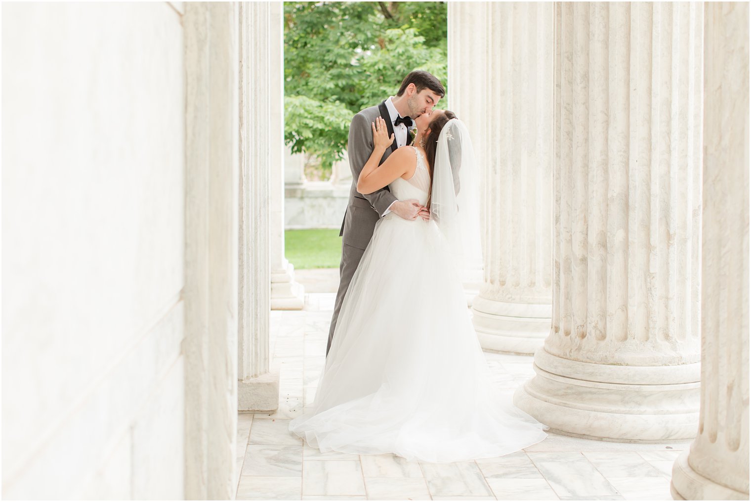 bride and groom kiss between columns at Princeton University