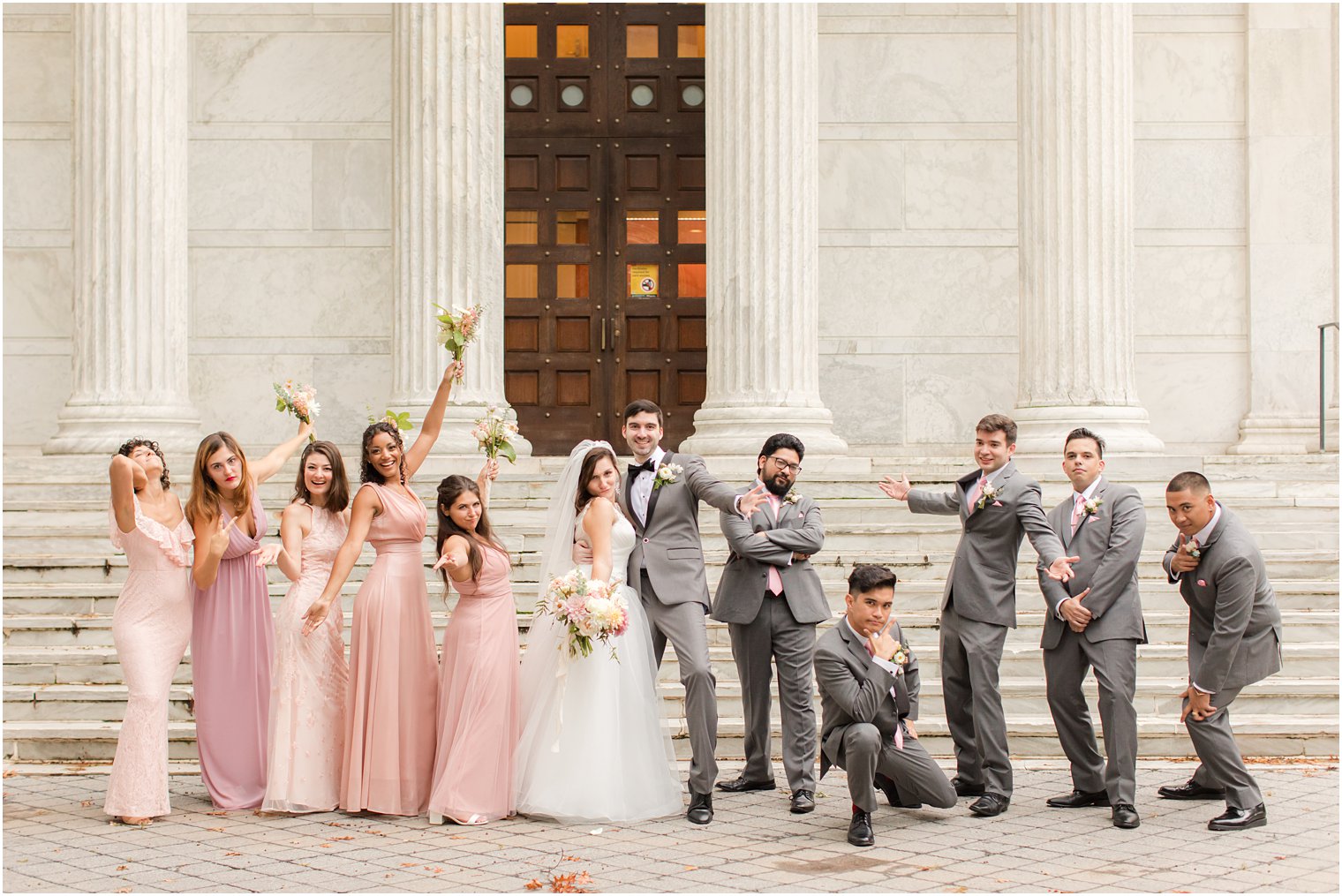 bride and groom pose with wedding party on steps of Princeton University