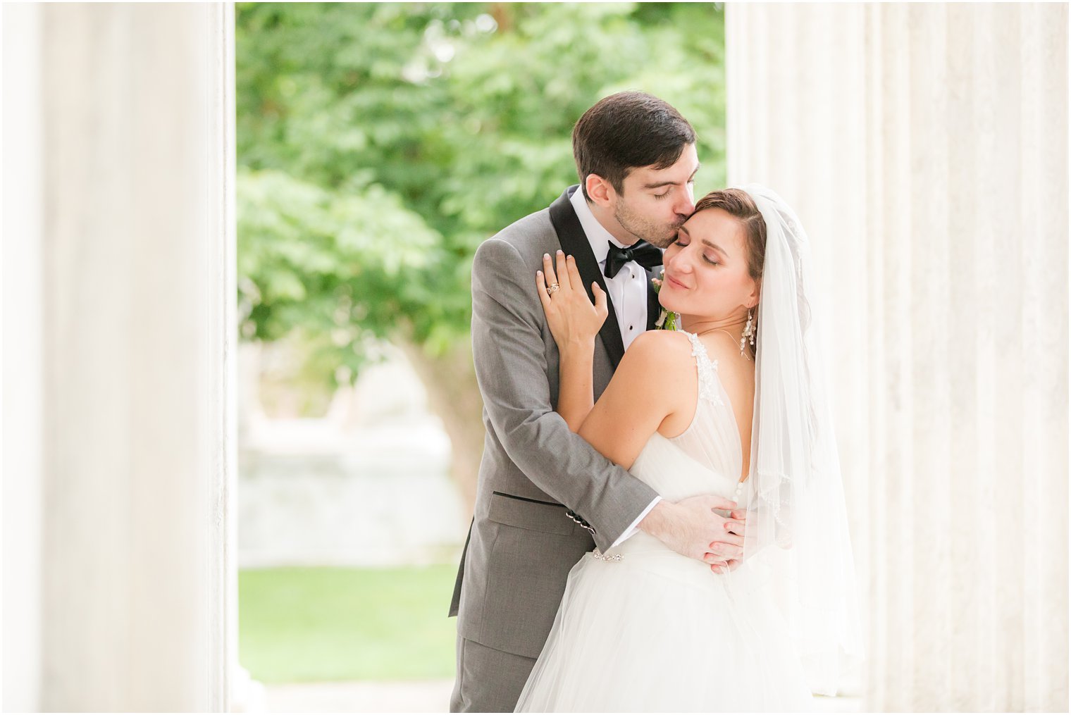 groom kisses bride's cheek between columns at Princeton University