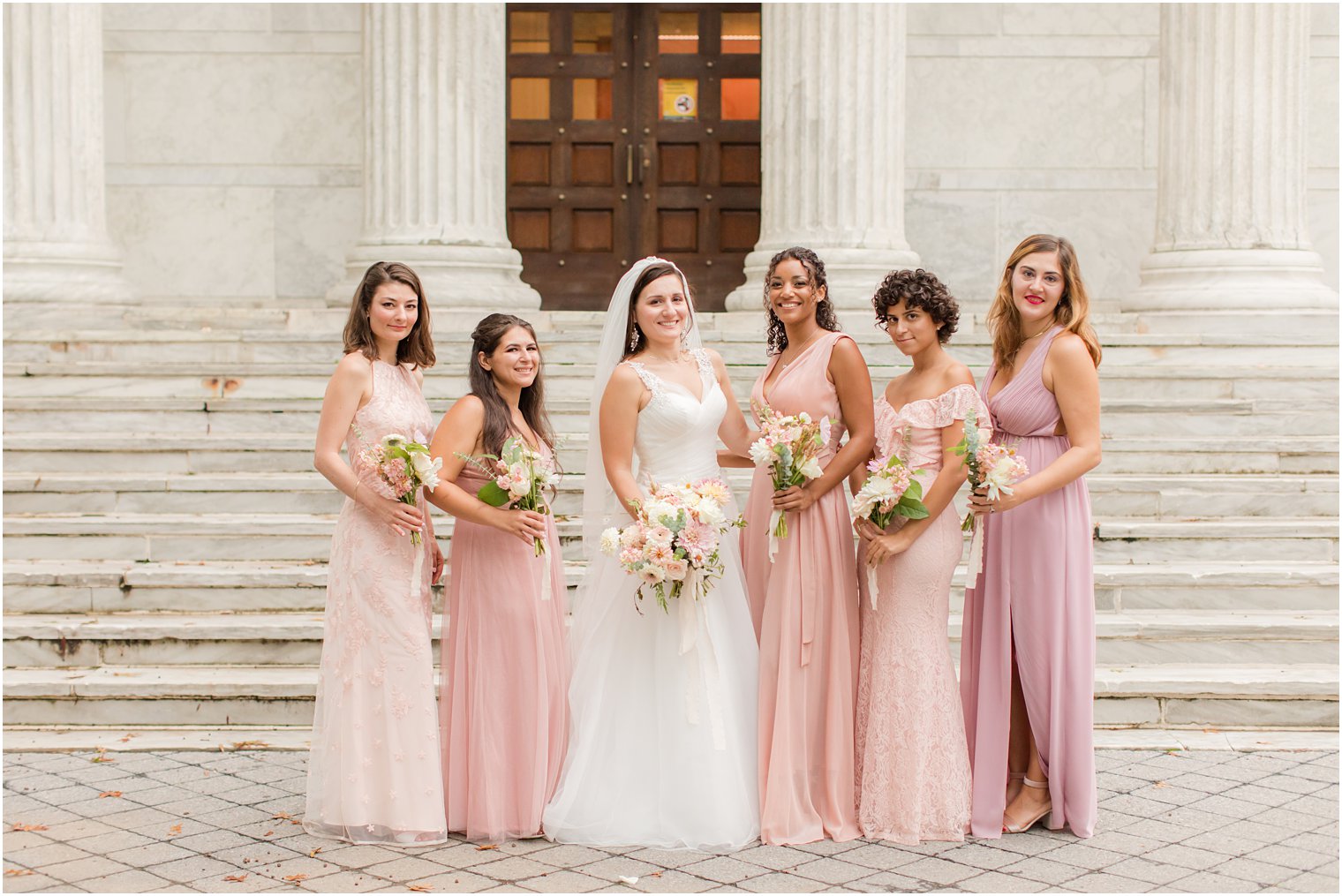 bride smiles with bridesmaids in pink gowns in New Jersey