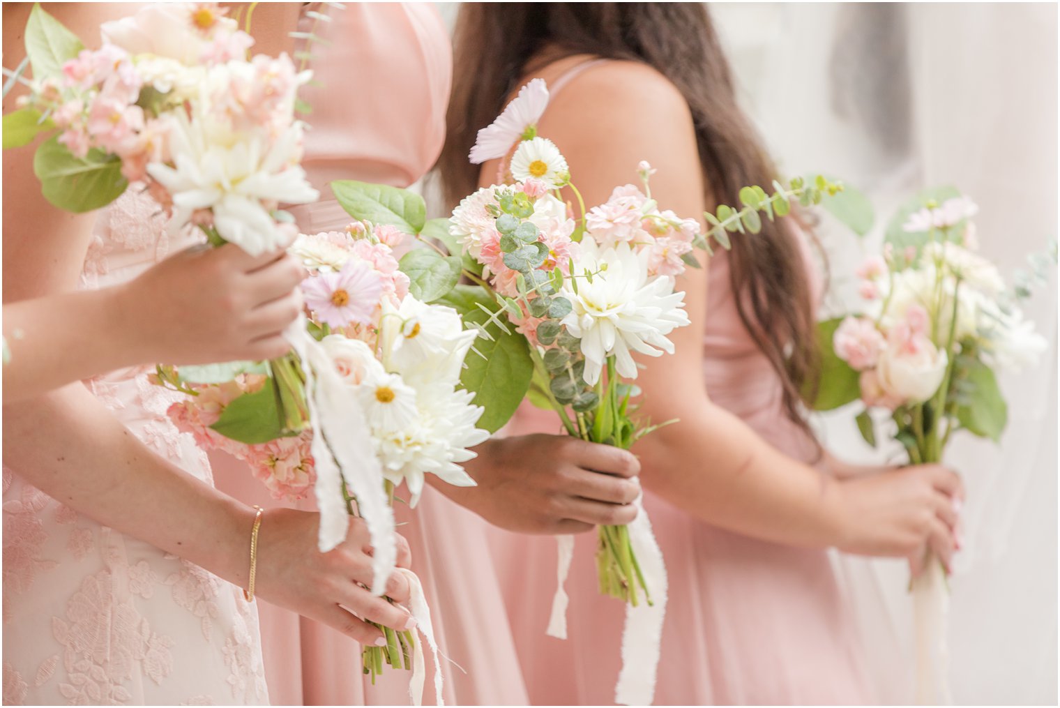 bridesmaids hold small bouquets of pink and white wildflowers