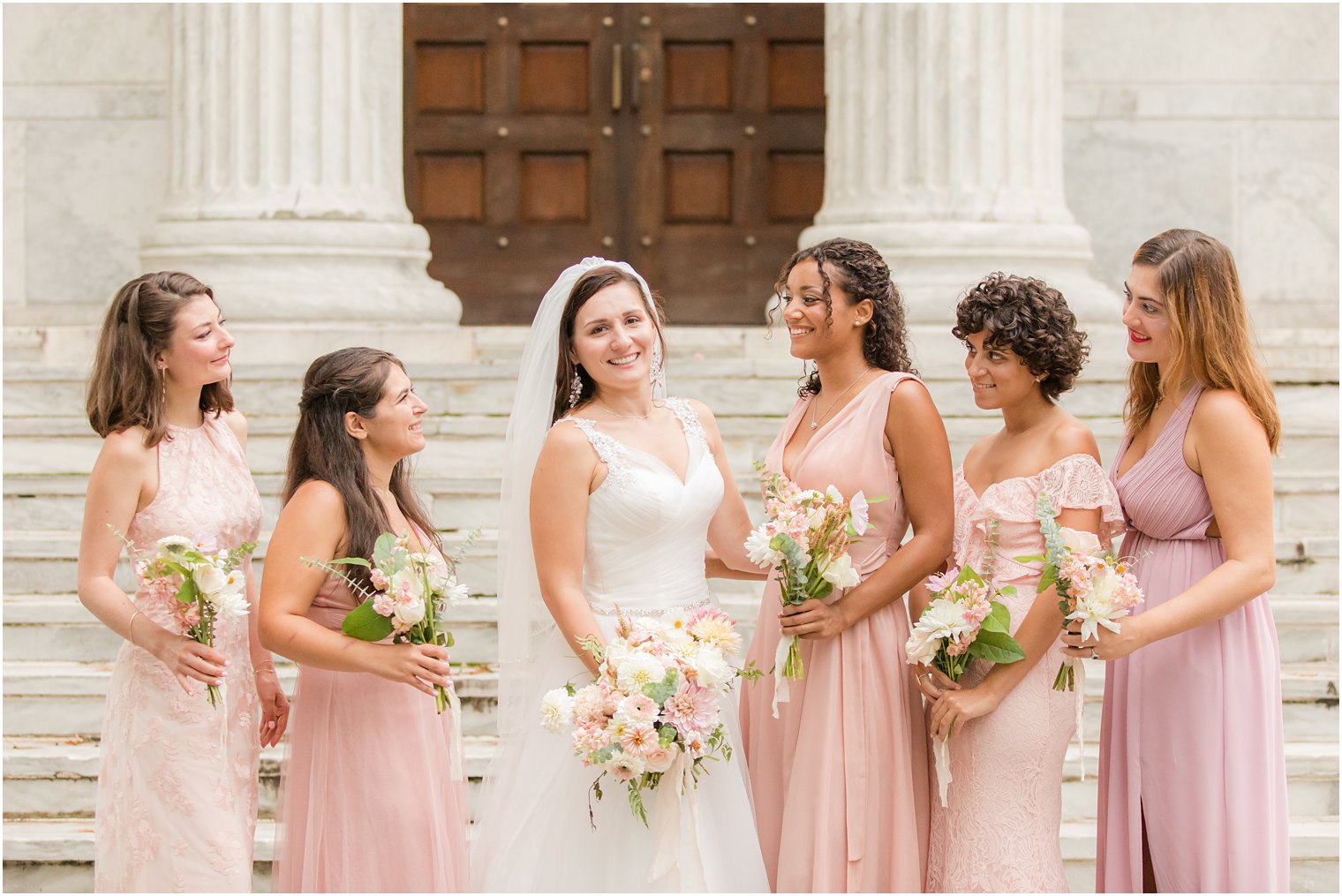 bride poses with bridesmaids in pink dresses at Princeton University