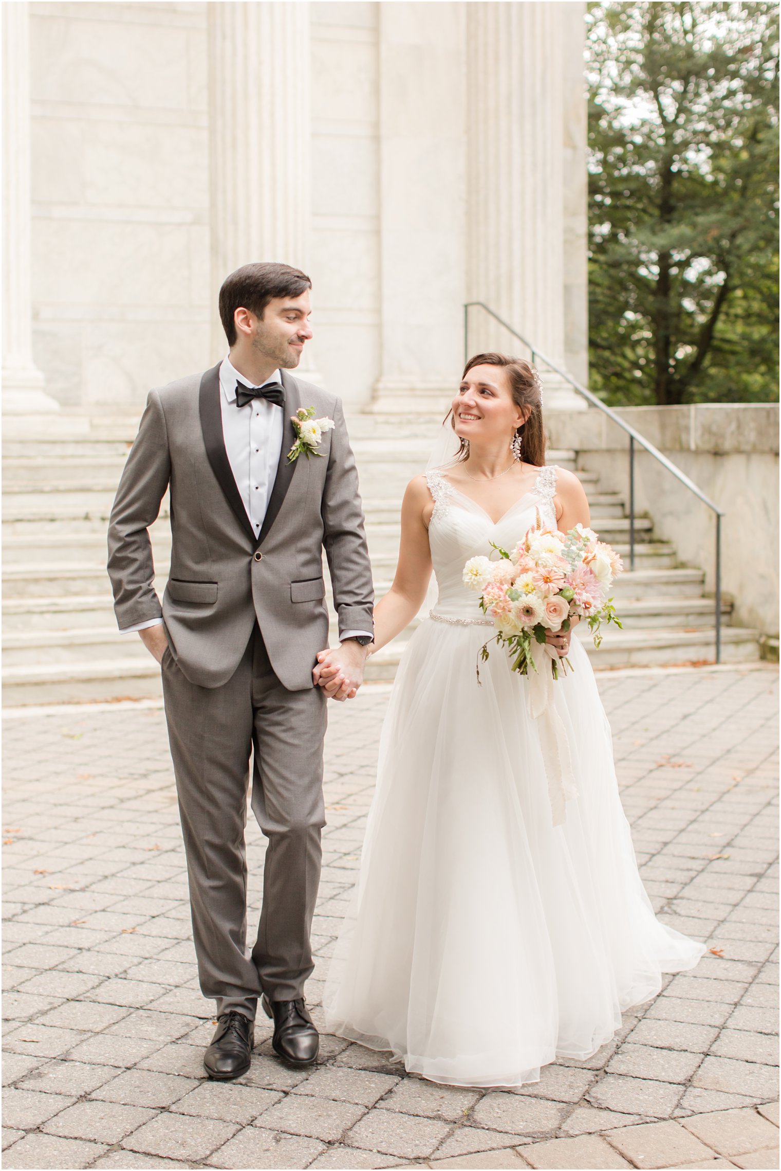 couple holds hands walking along buildings at Princeton University