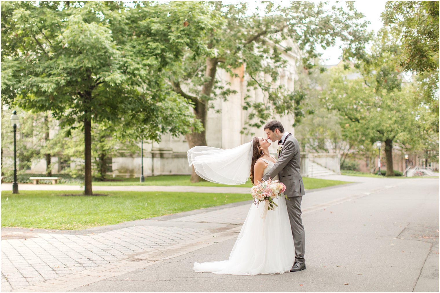 groom kisses bride with veil floating behind her at Princeton University