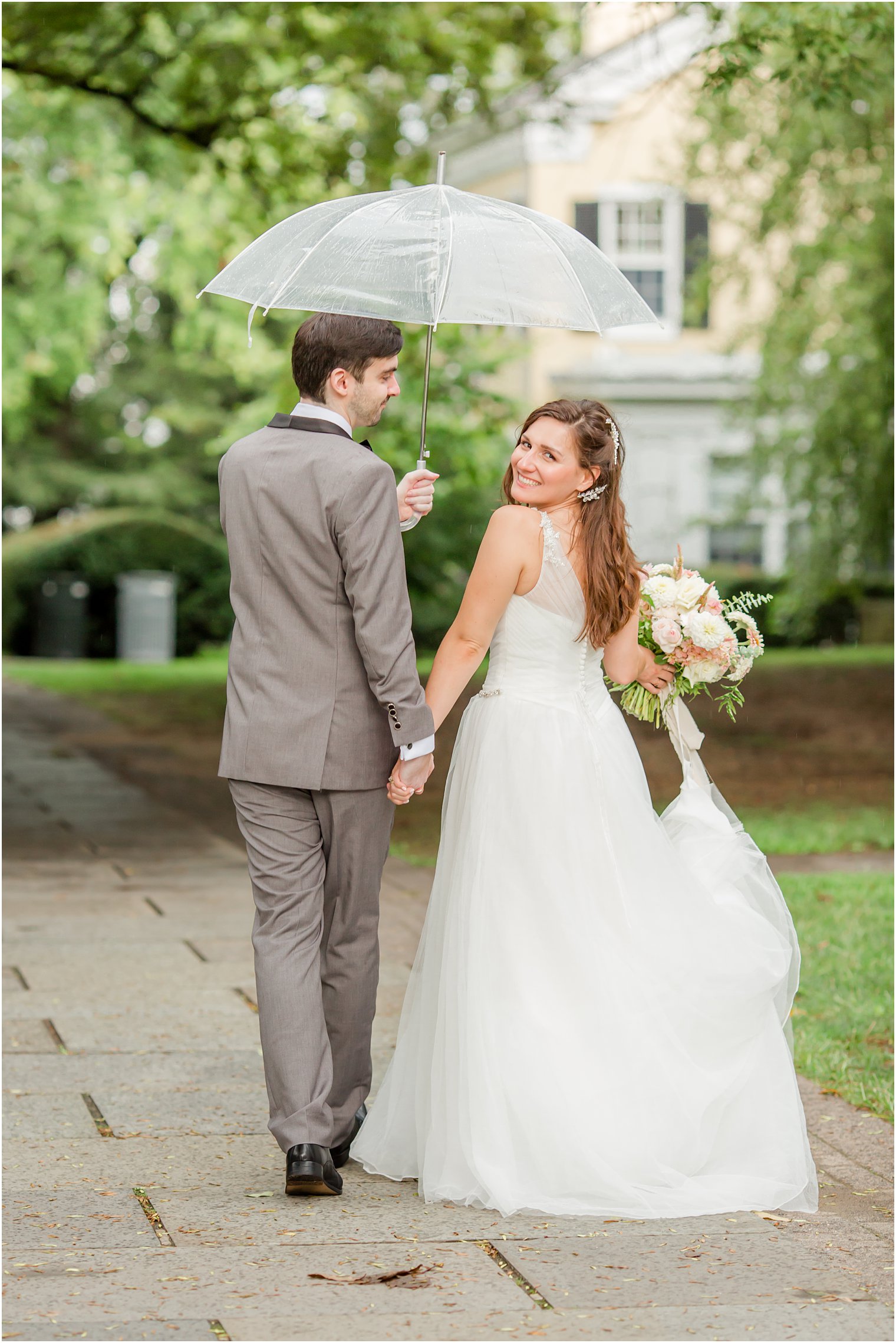 bride and groom walk under umbrella at Princeton University
