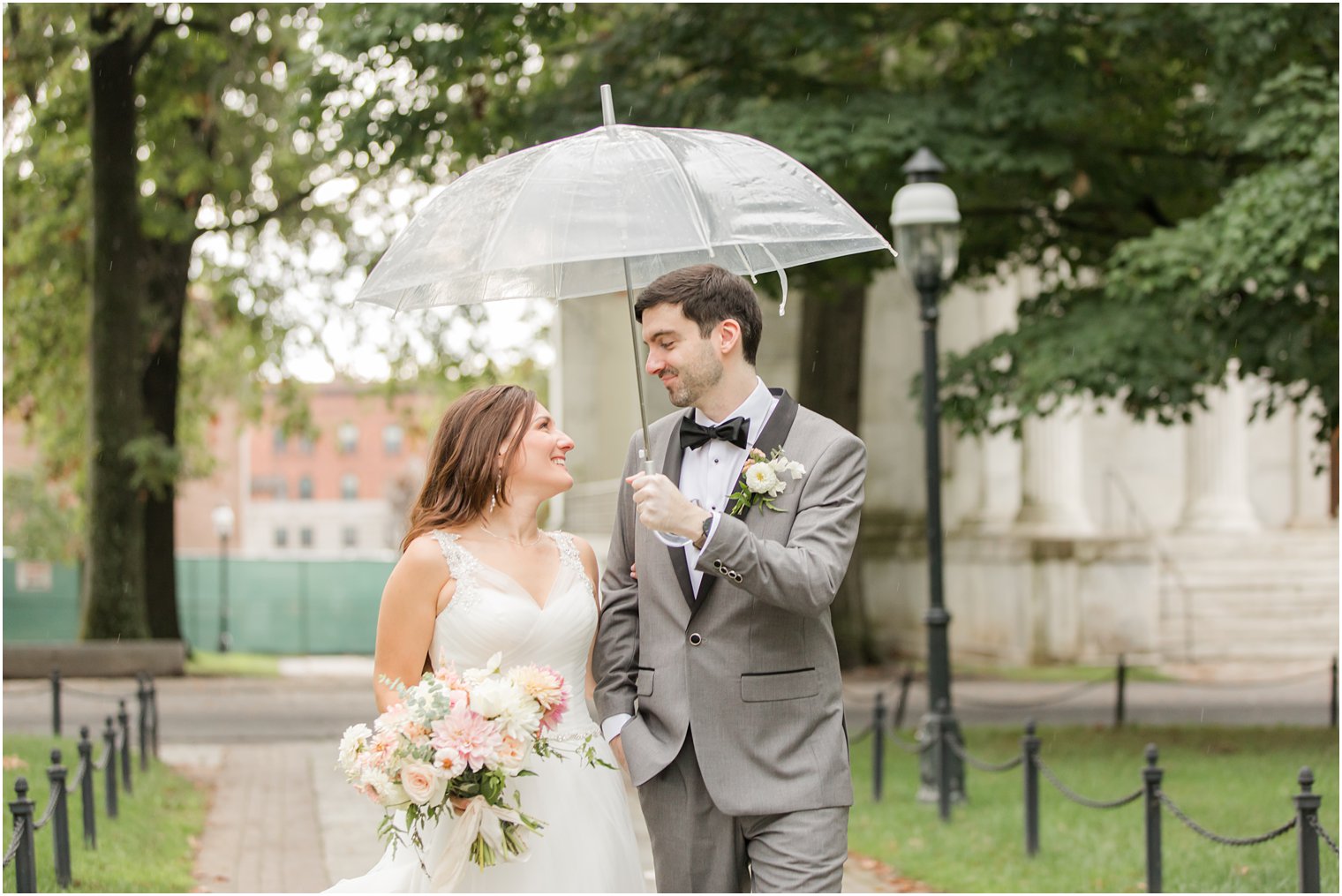 newlyweds walk under clear umbrella in Princeton NJ