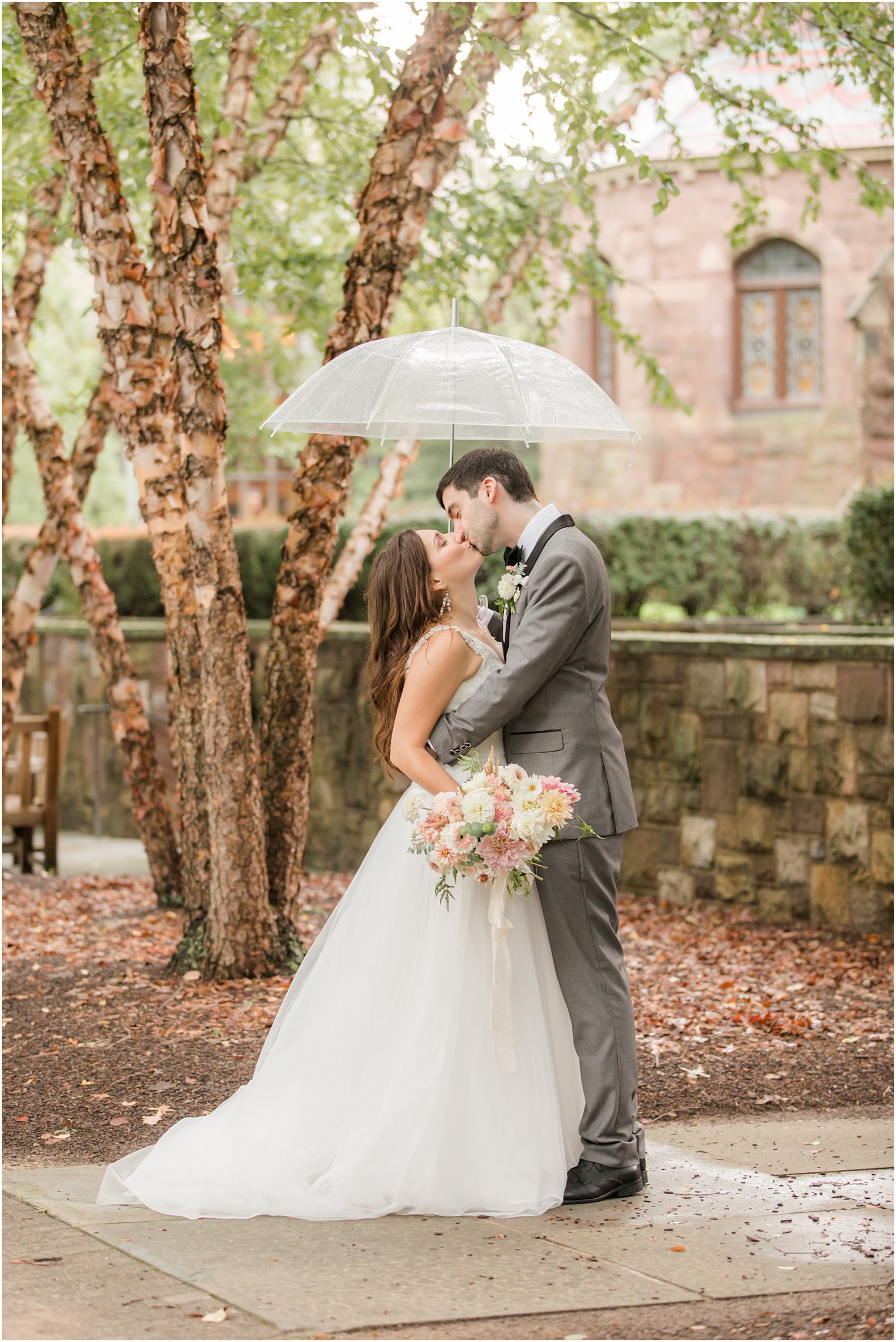 bride and groom kiss under umbrella on wedding day in Princeton NJ
