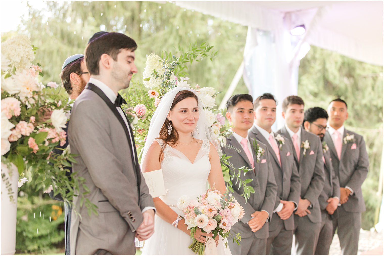 bride and groom smile during NJ wedding ceremony under tent at Chauncey Hotel