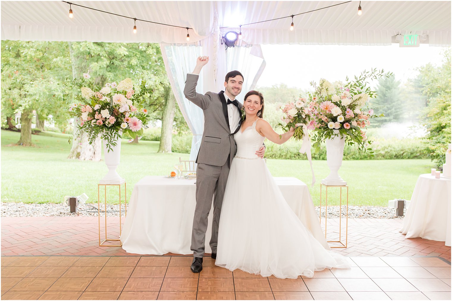 bride and groom pose by sweetheart table under tent at NJ wedding reception