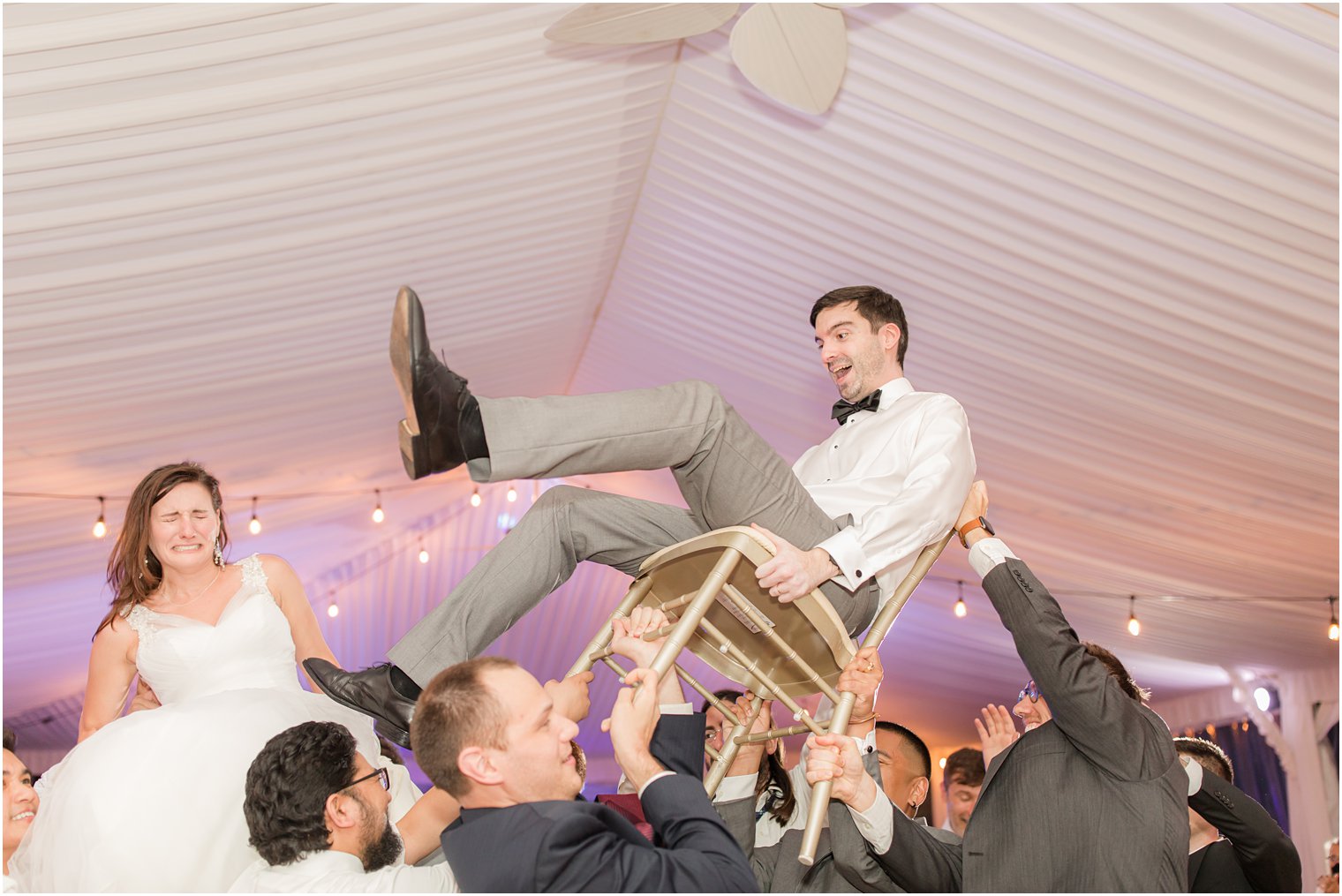 couple is lifted up in chairs during NJ wedding reception