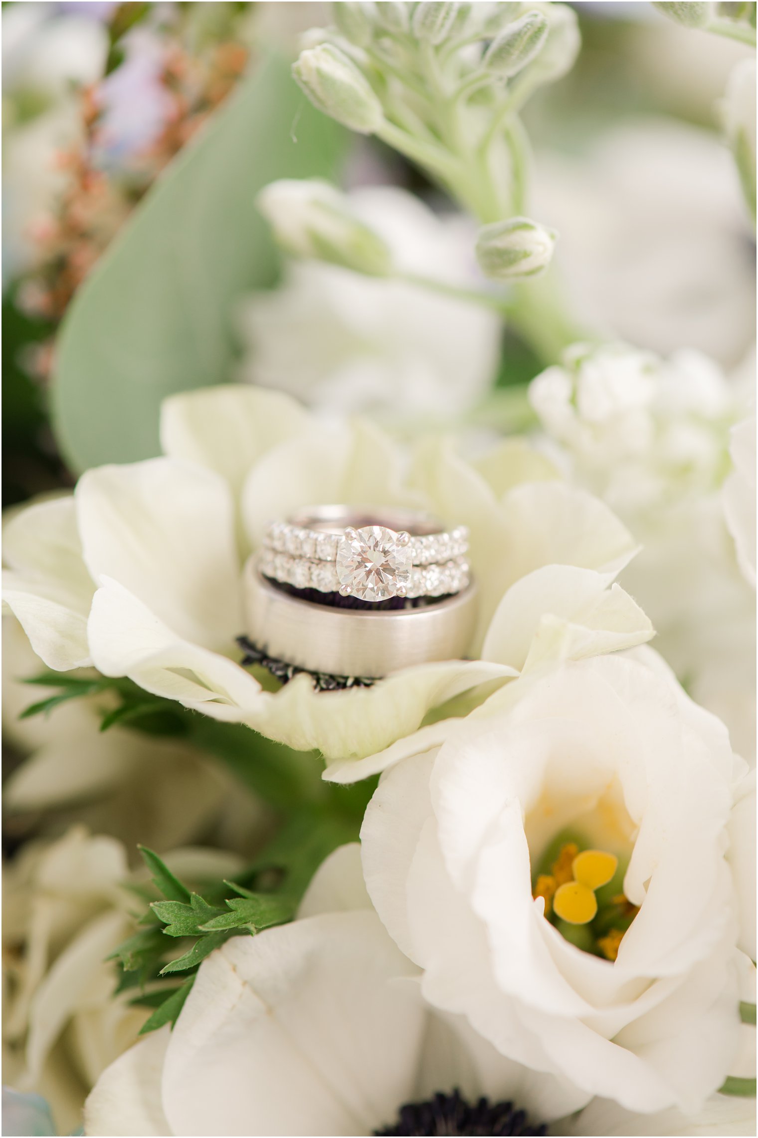 wedding rings rest on white flowers before NJ wedding