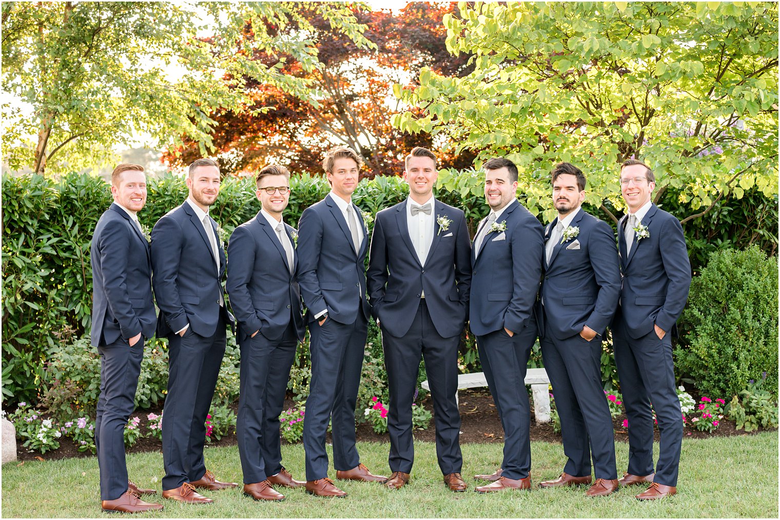 groom and groomsmen in navy suits pose together in Point Pleasant