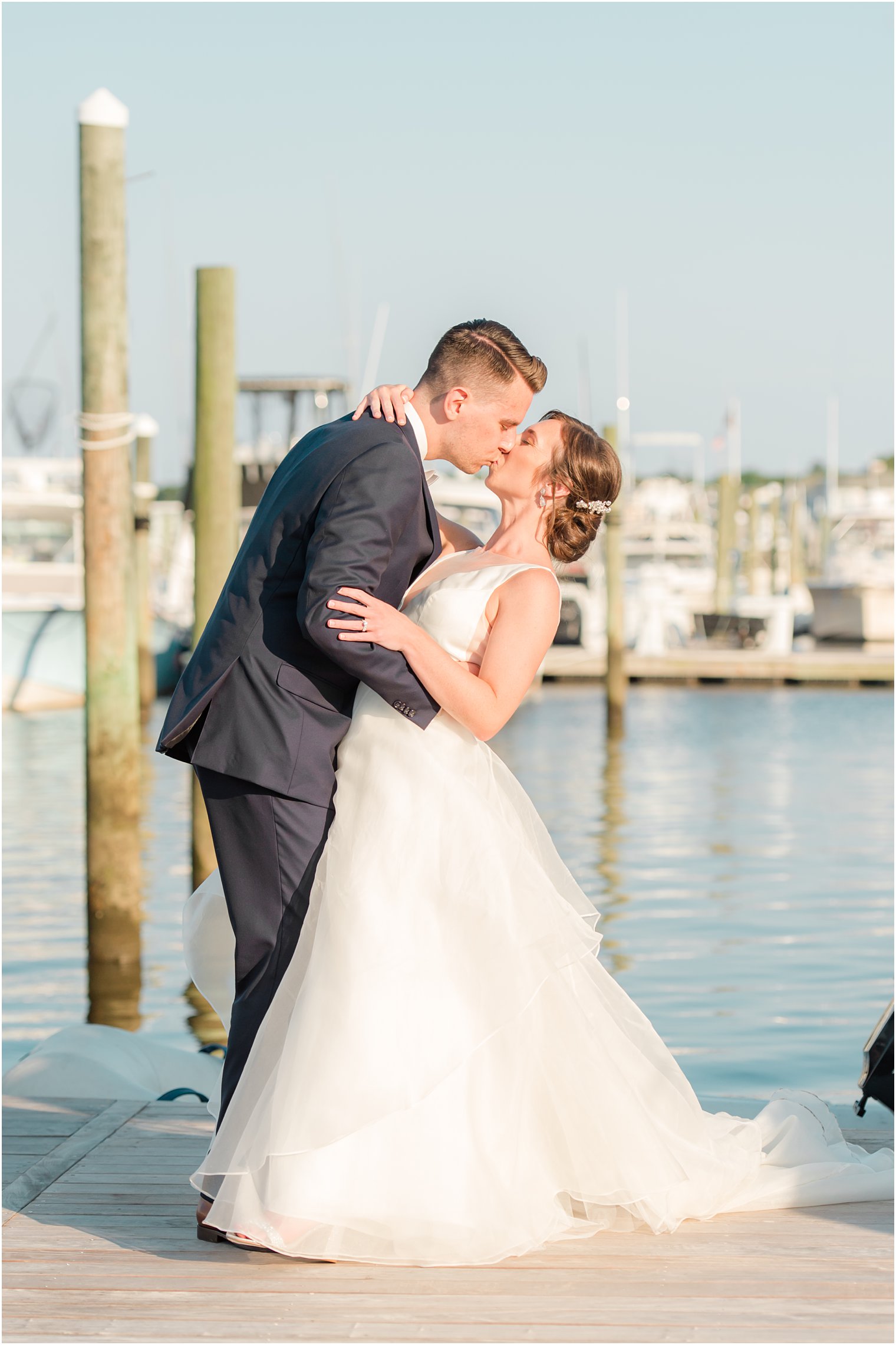 newlyweds kiss on docks during wedding photos at Crystal Point Yacht Club