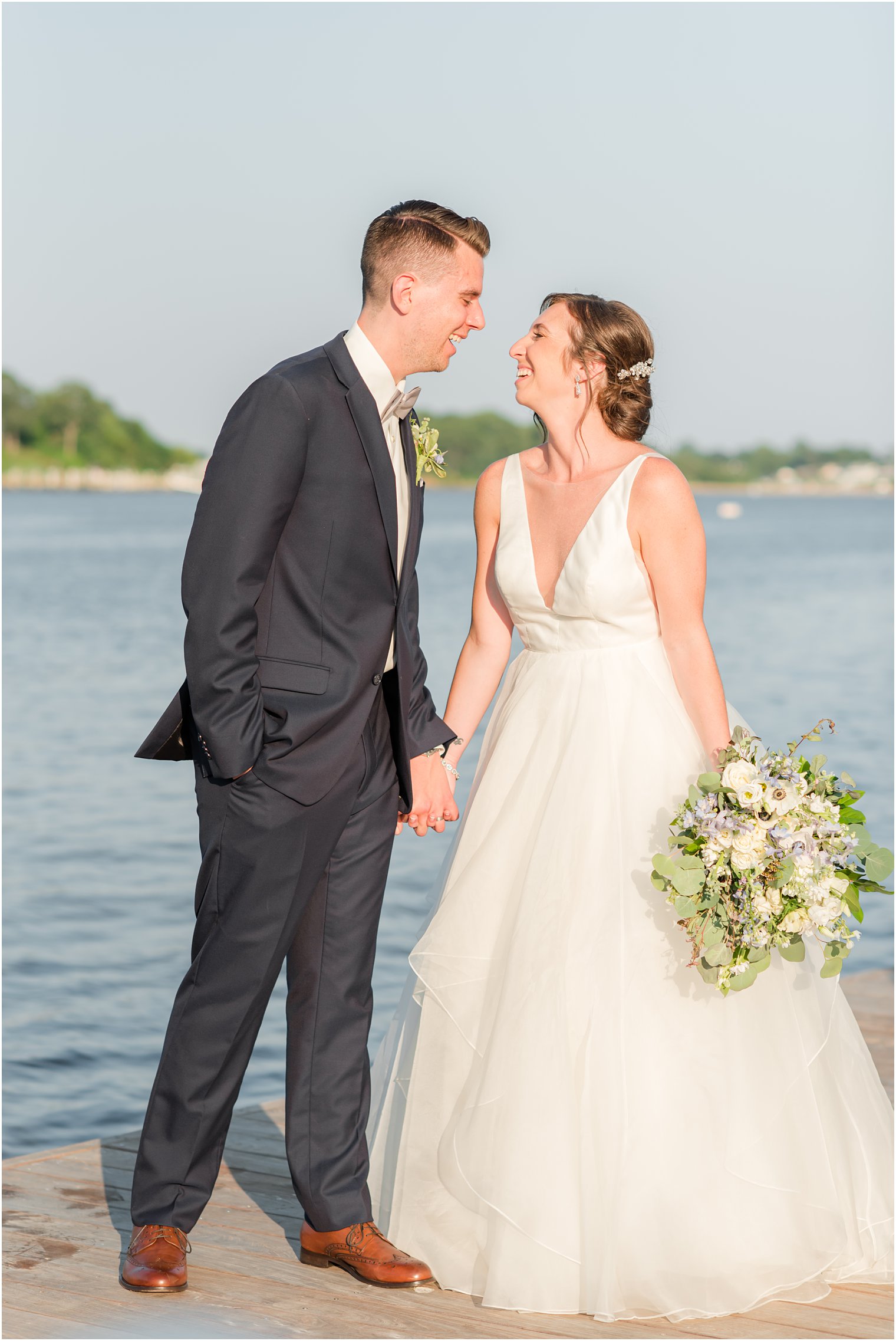 bride and groom hold hands laughing during Crystal Point Yacht Club wedding photos