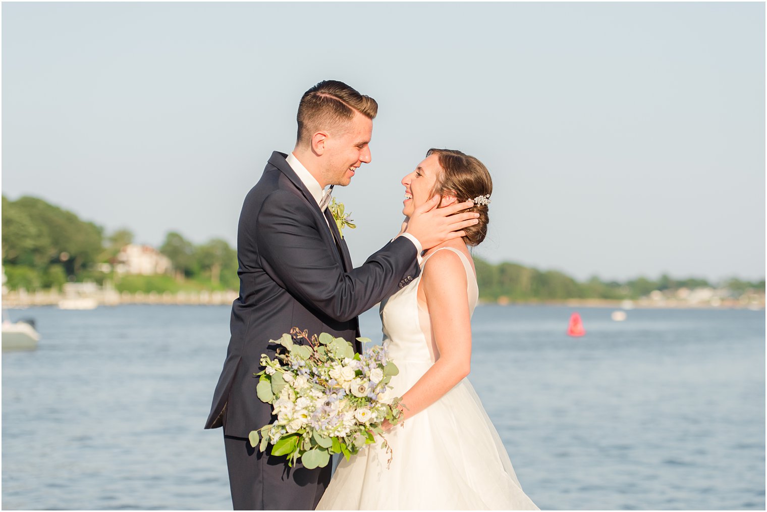 groom looks at bride during wedding photos along water in Point Pleasant