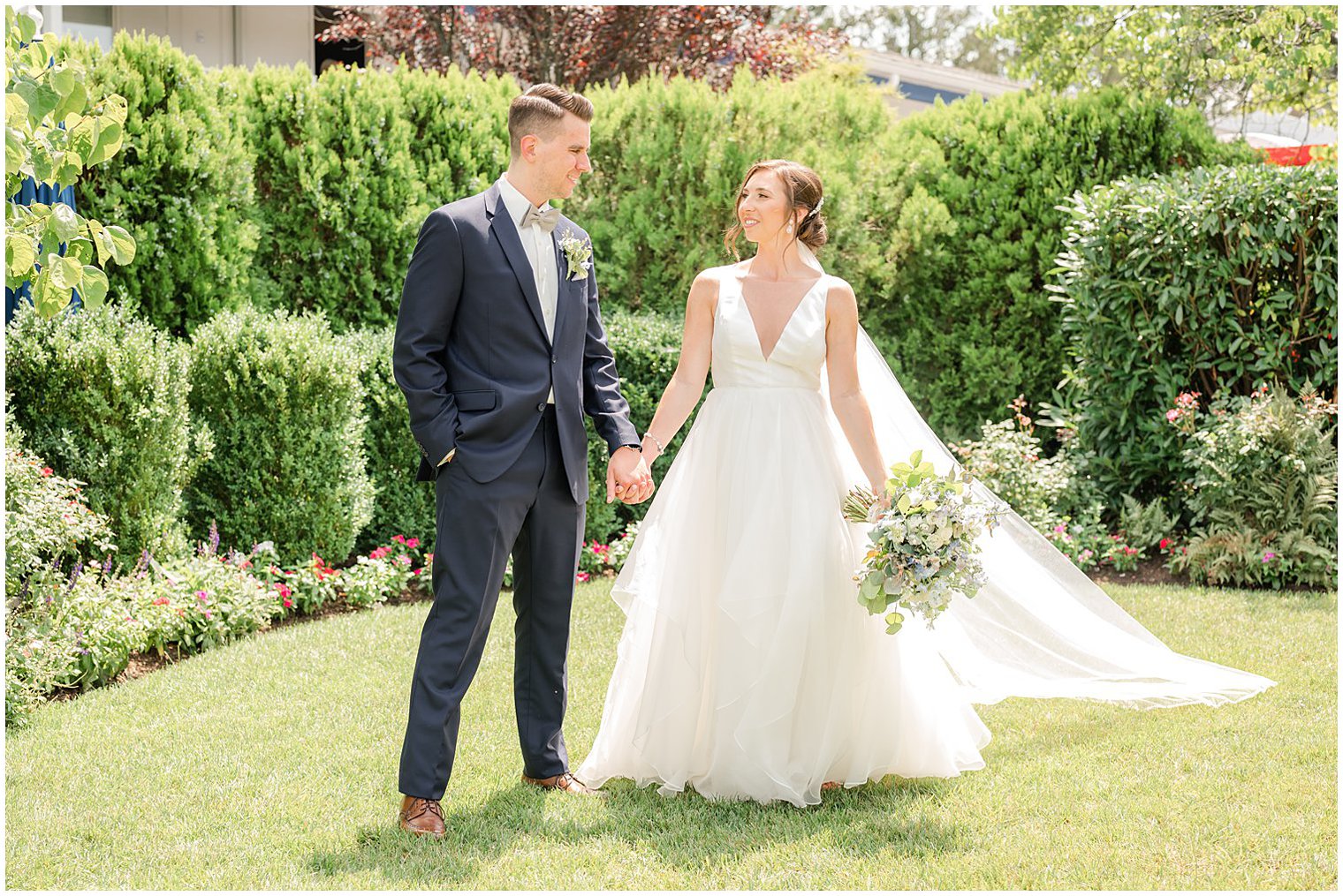 bride and groom hold hands walking through lawn at Crystal Point Yacht Club