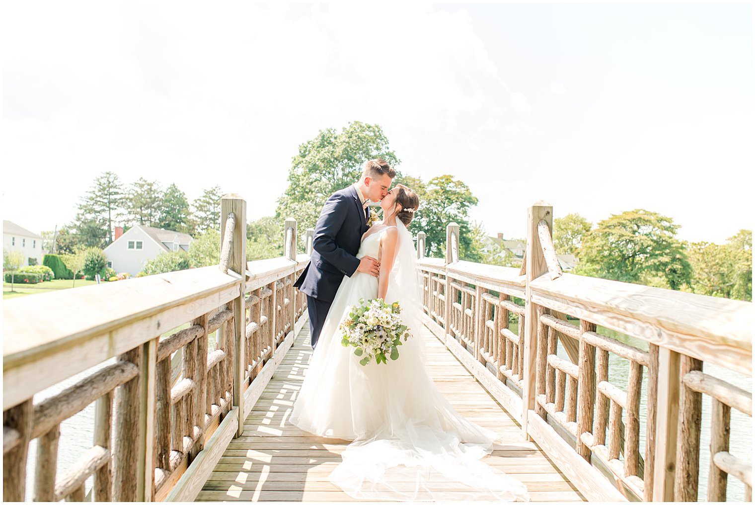 bride and groom kiss on wooden bridge at Crystal Point Yacht Club