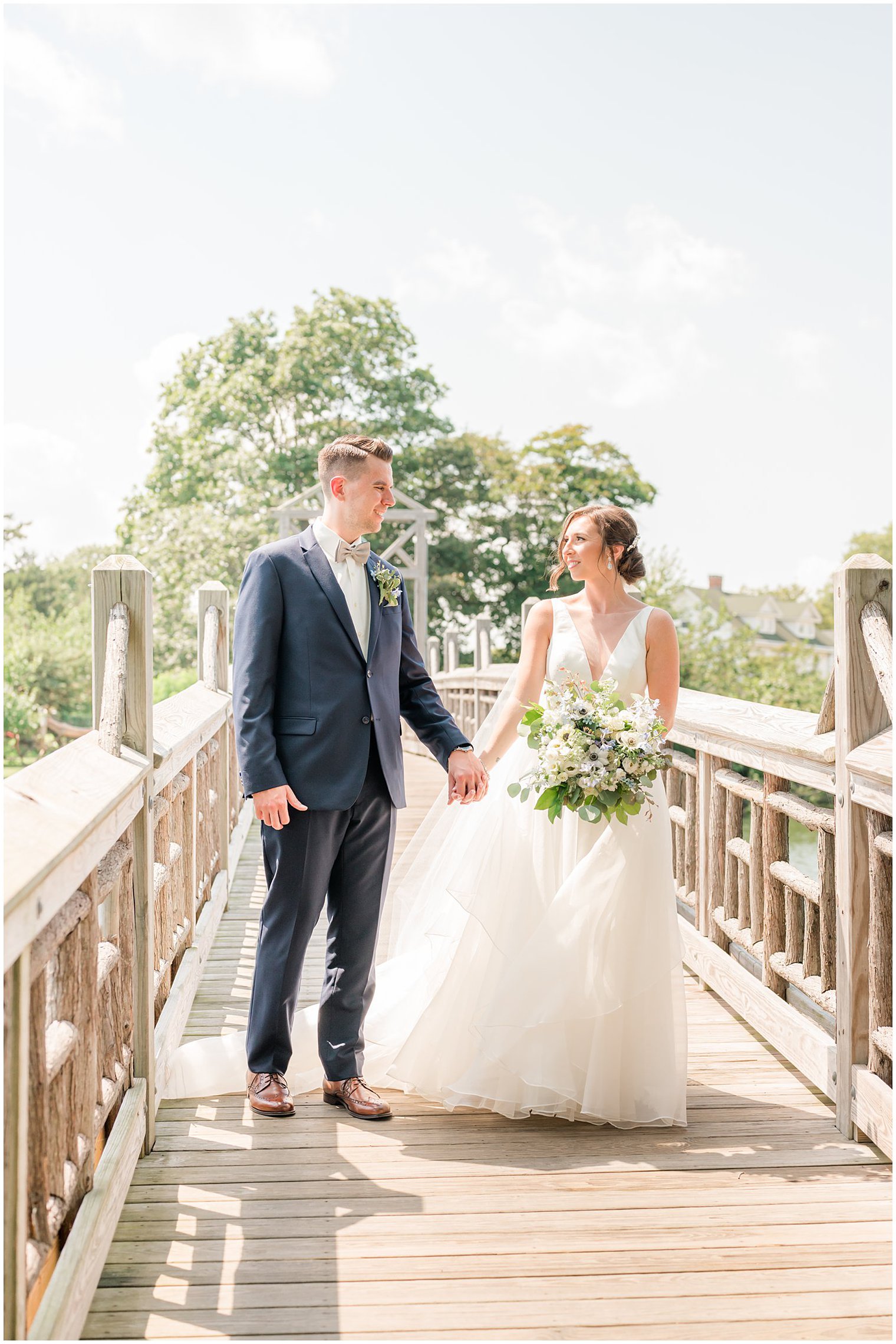 newlyweds hold hands walking on wooden bridge in New Jersey
