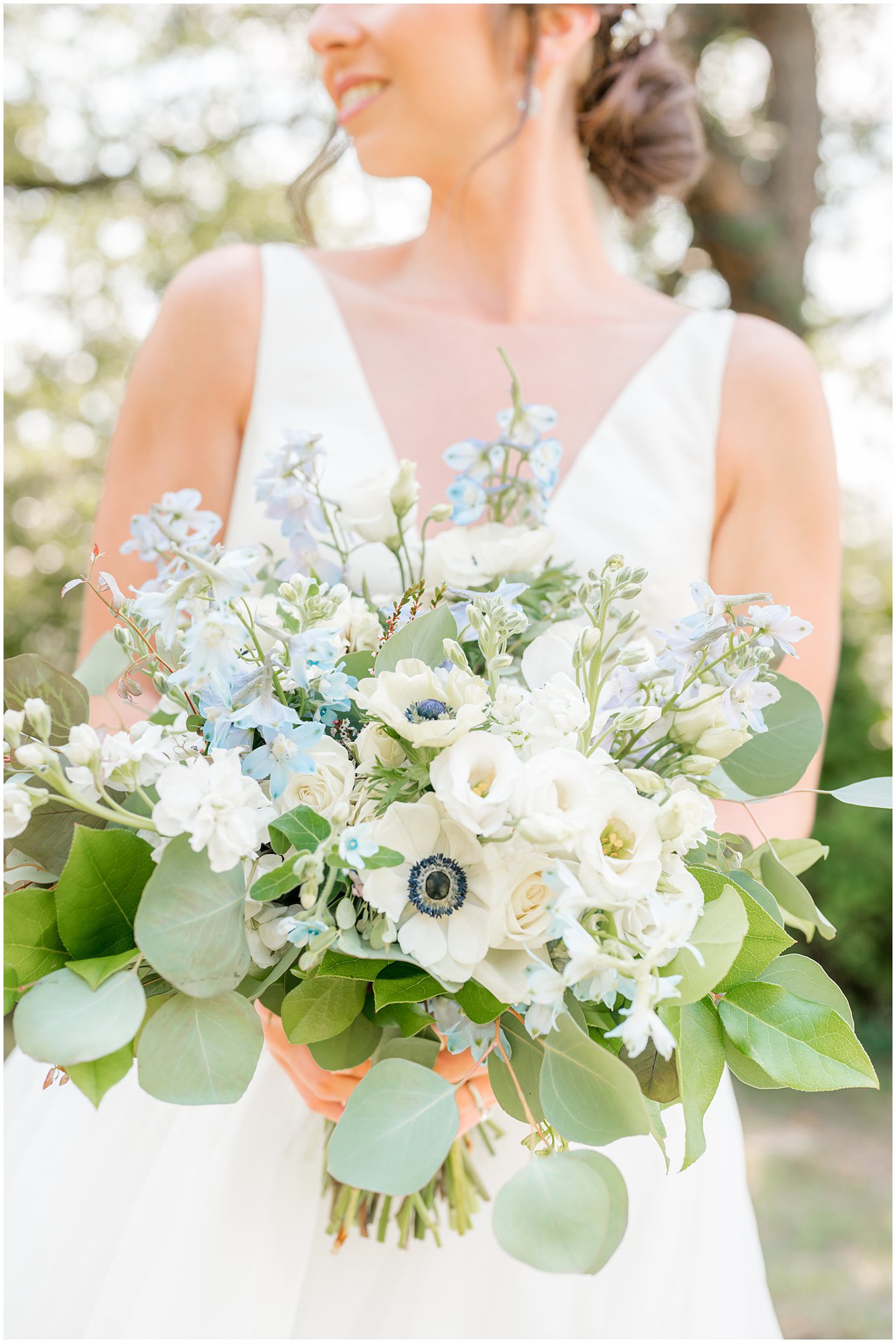 bride holds summer bouquet of white, ivory, and blue flowers