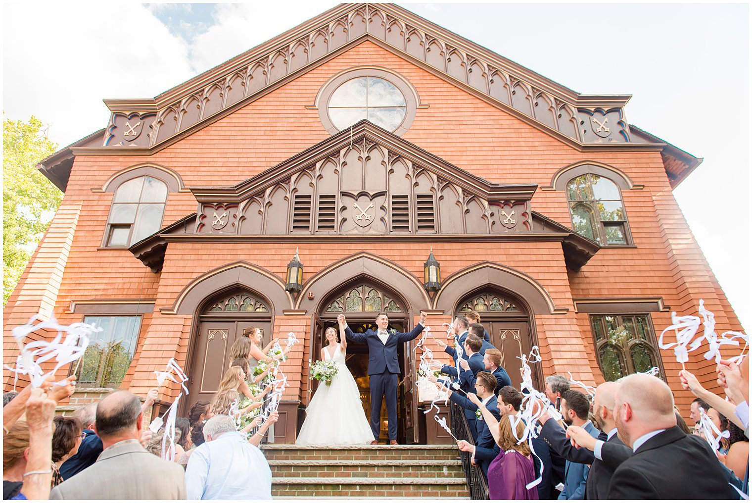 bride and groom leave church with guests waving ribbons