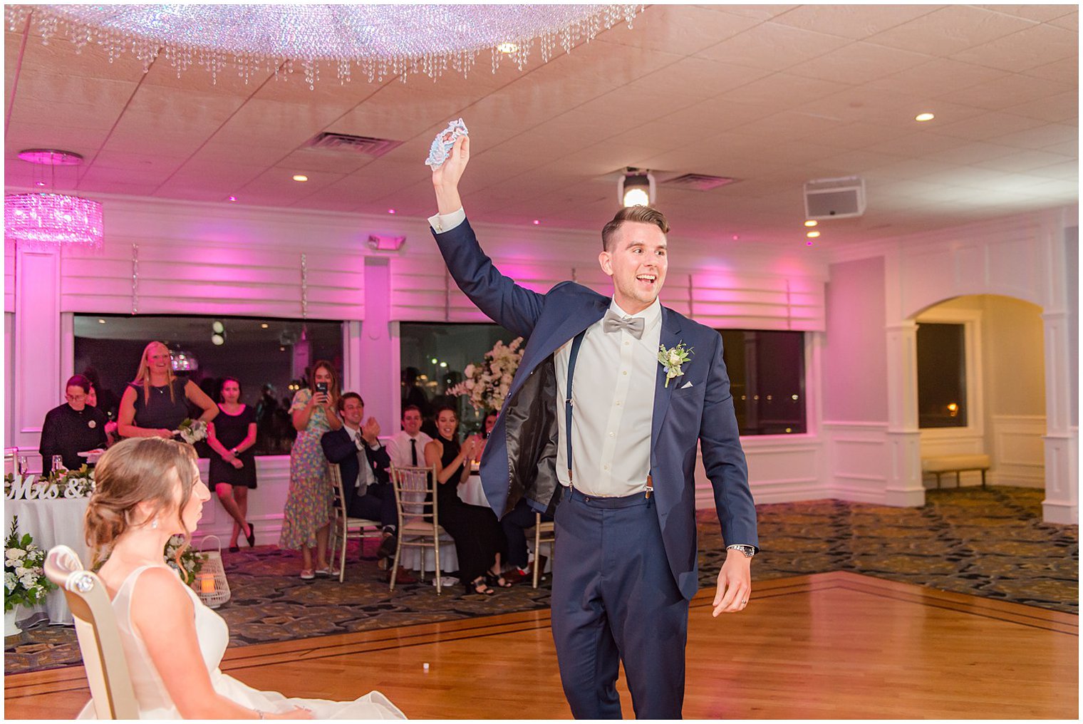 groom holds up garter during NJ wedding reception