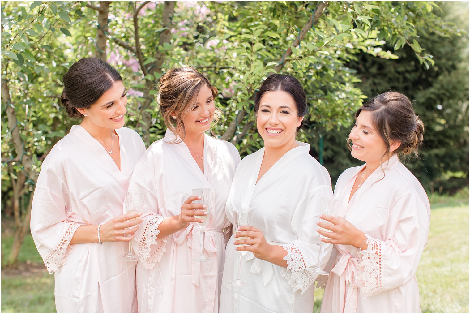 bride and bridal party hold champagne flutes in matching robes 