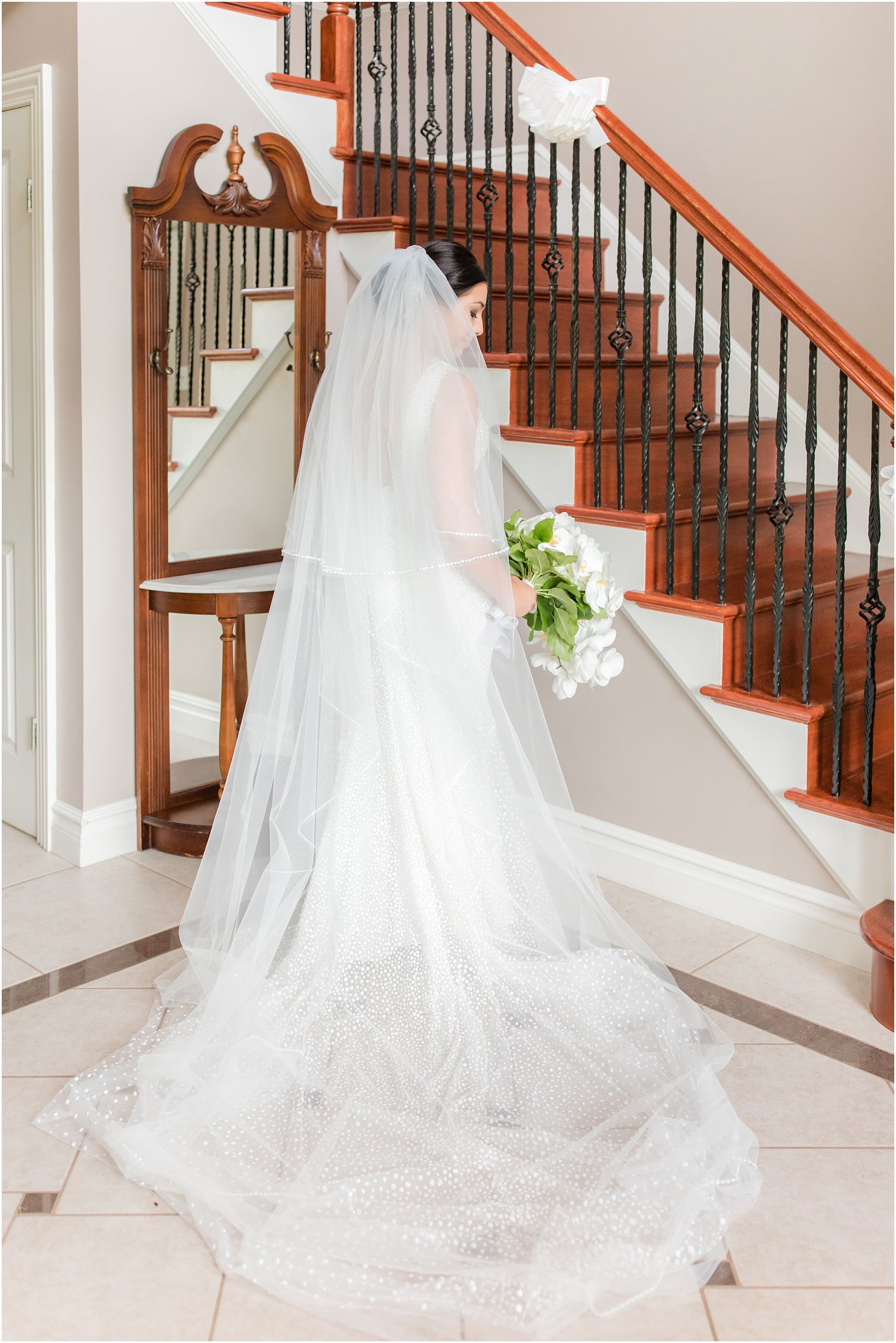 bride poses by staircase with veil behind her