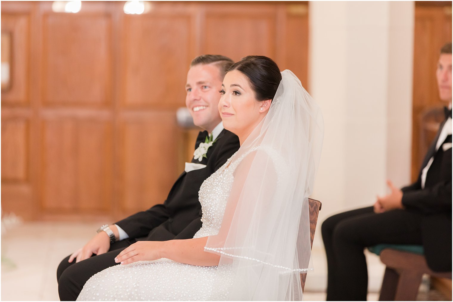 newlyweds sit during traditional wedding ceremony at St. James church