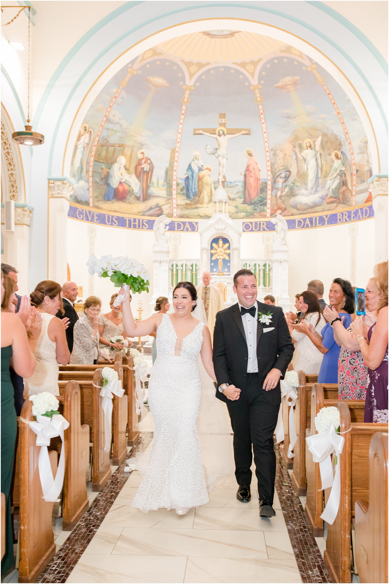 bride and groom smile walking up aisle after traditional wedding ceremony at St. James church