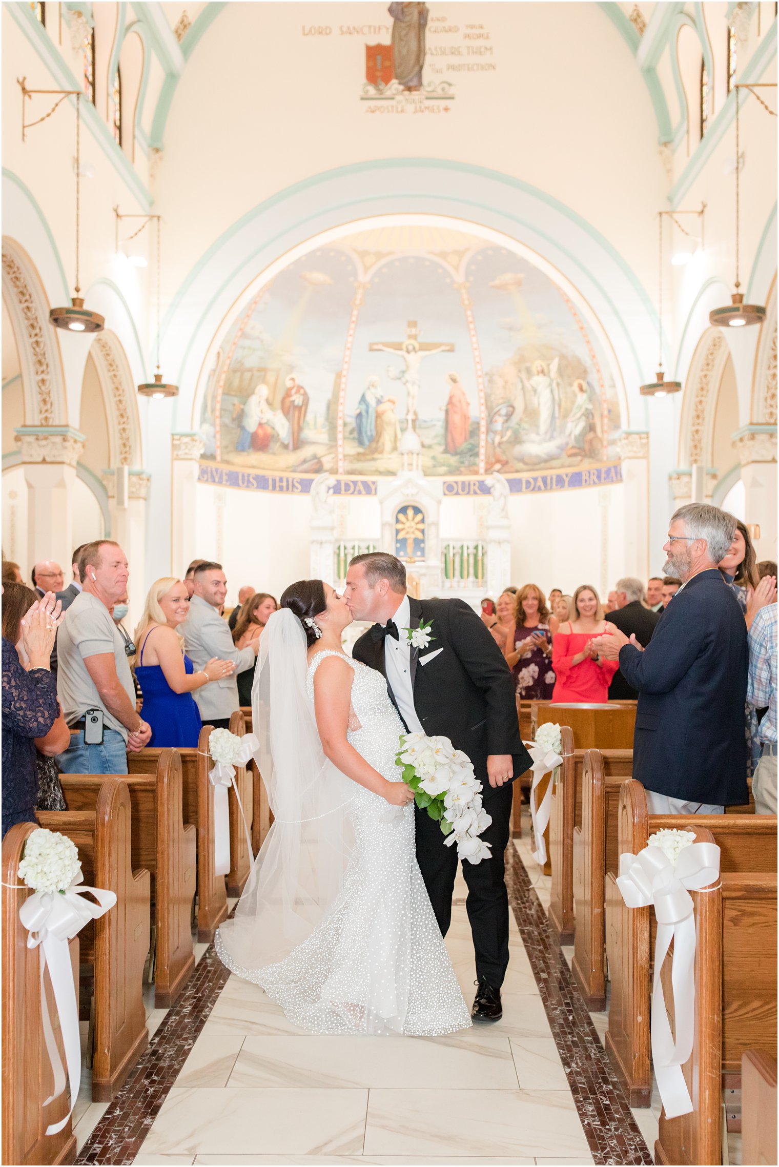 bride and groom kiss after traditional wedding ceremony at St. James church