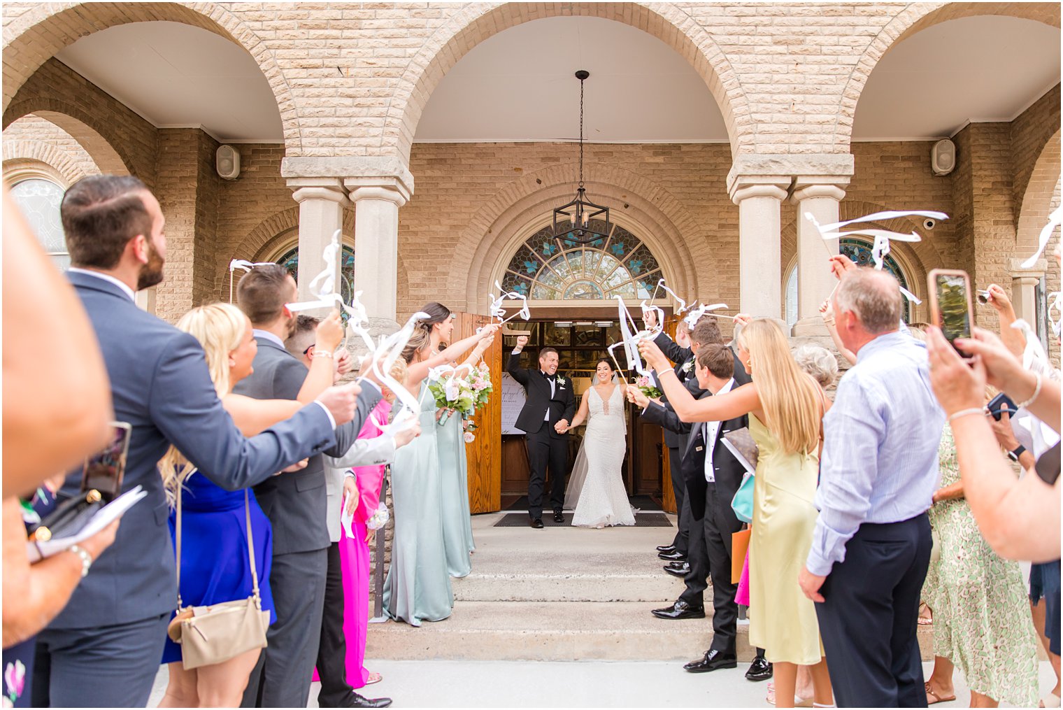 guests wave ribbons for newlyweds after traditional wedding ceremony at St. James church