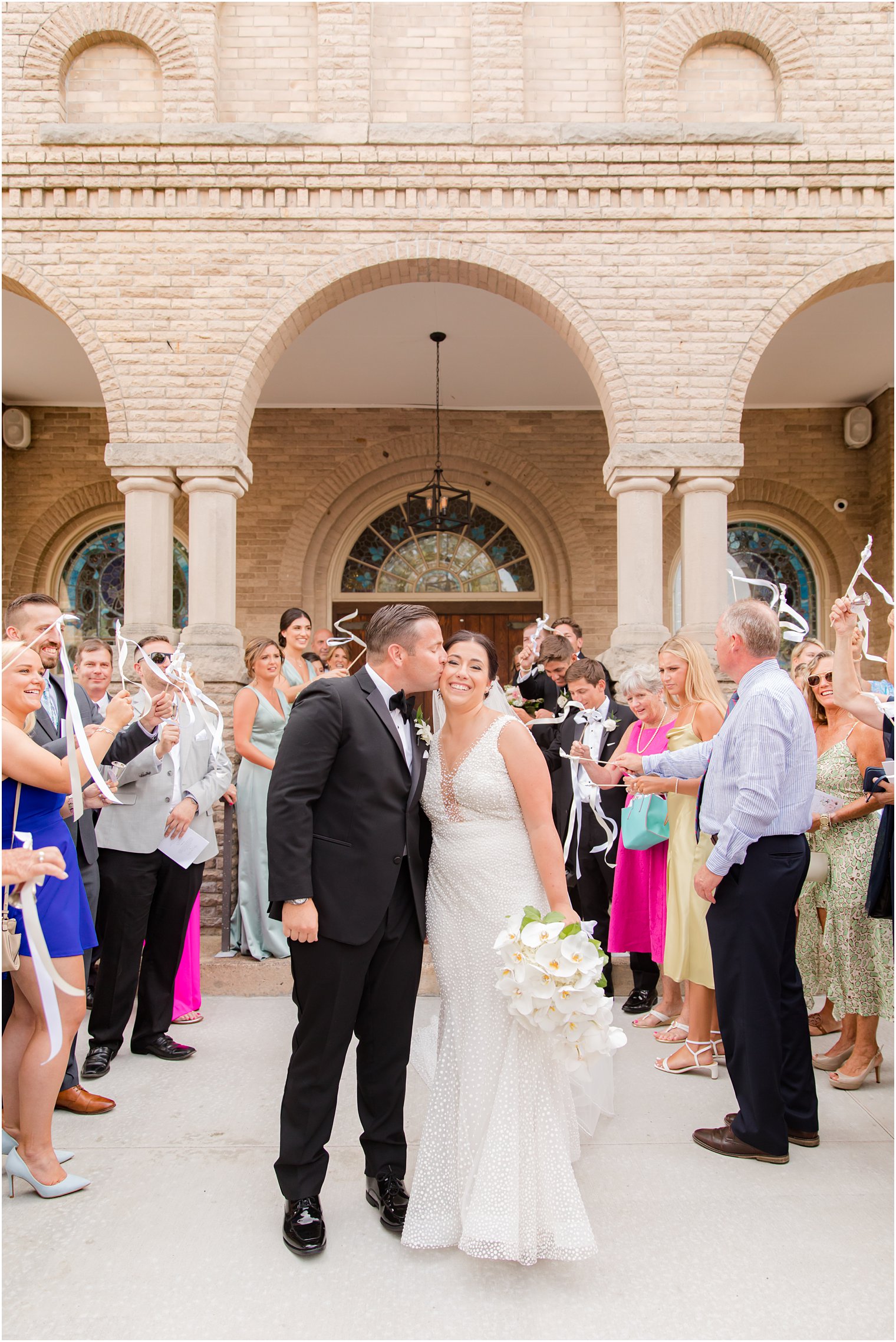 groom kisses bride's cheek during NJ wedding photos at church