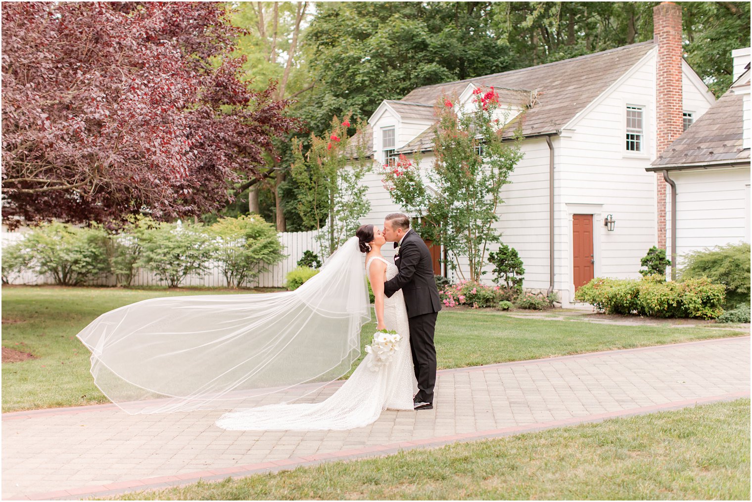 bride and groom kiss with veil floating behind her