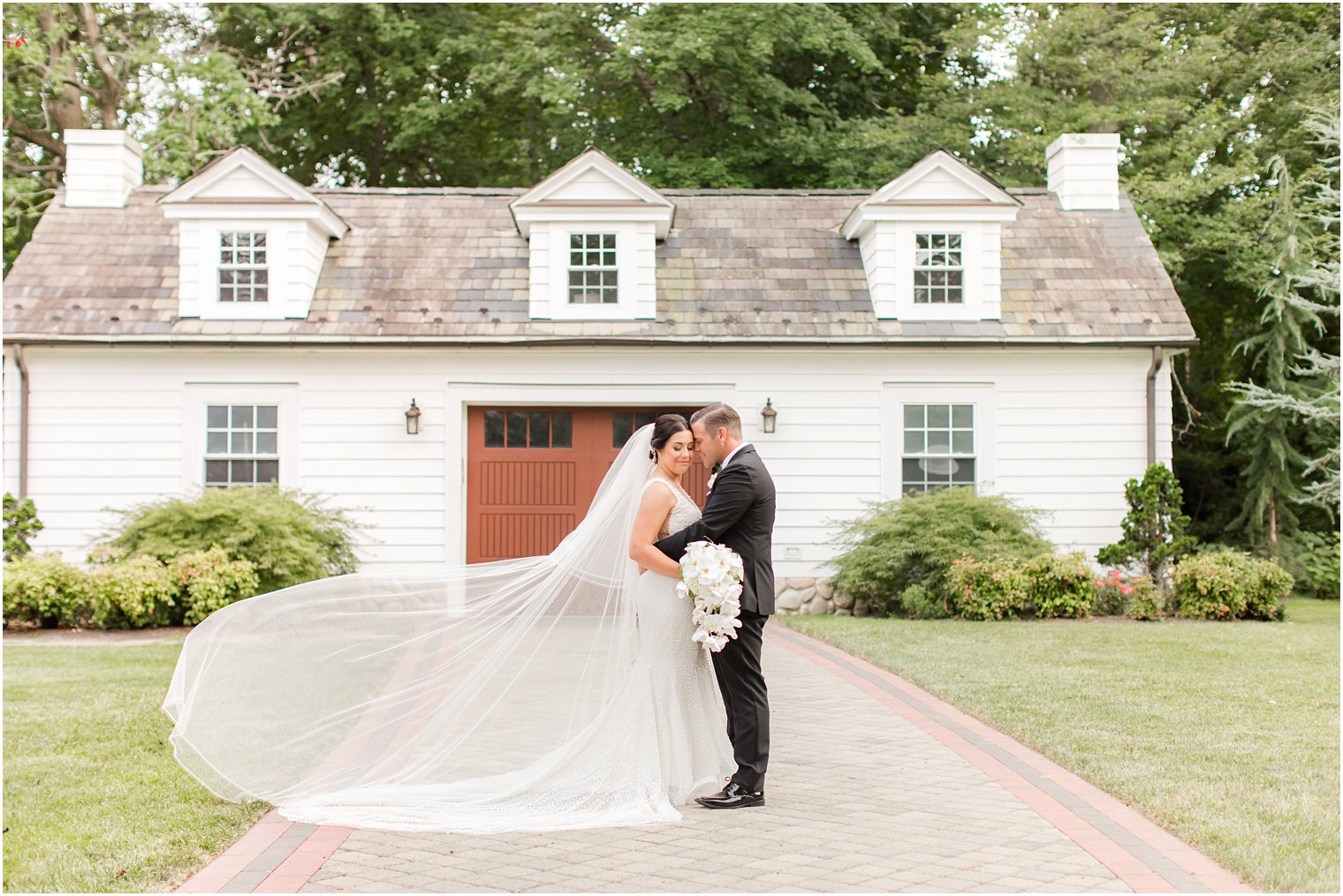 bride and groom hug at The English Manor with bride's veil floating 