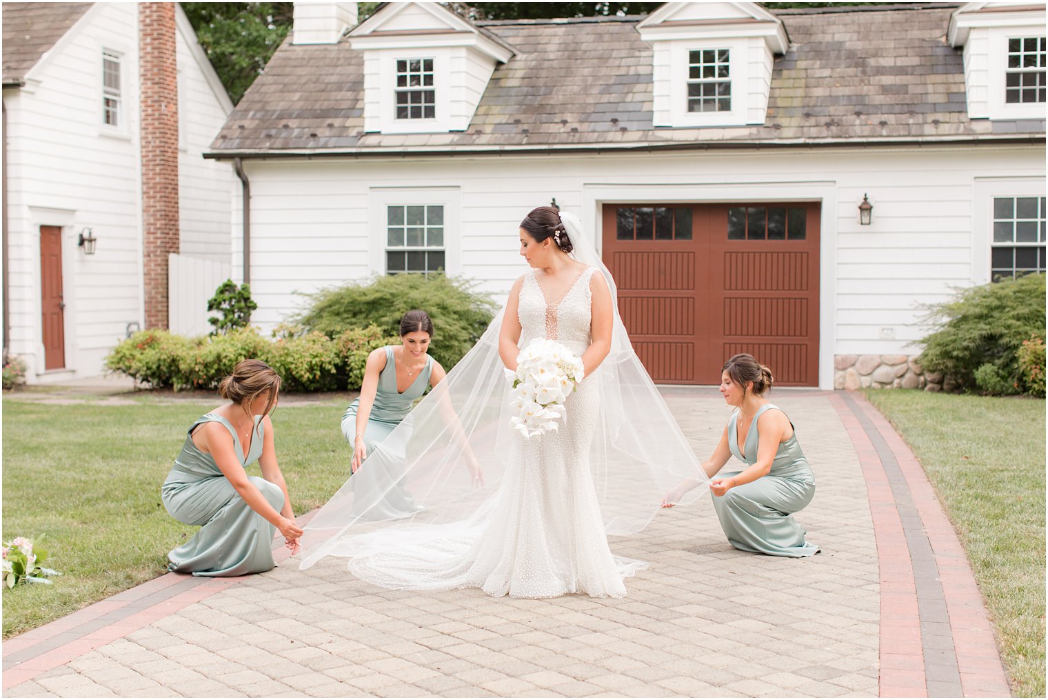 bridesmaids in mint green help bride with veil outside The English manor