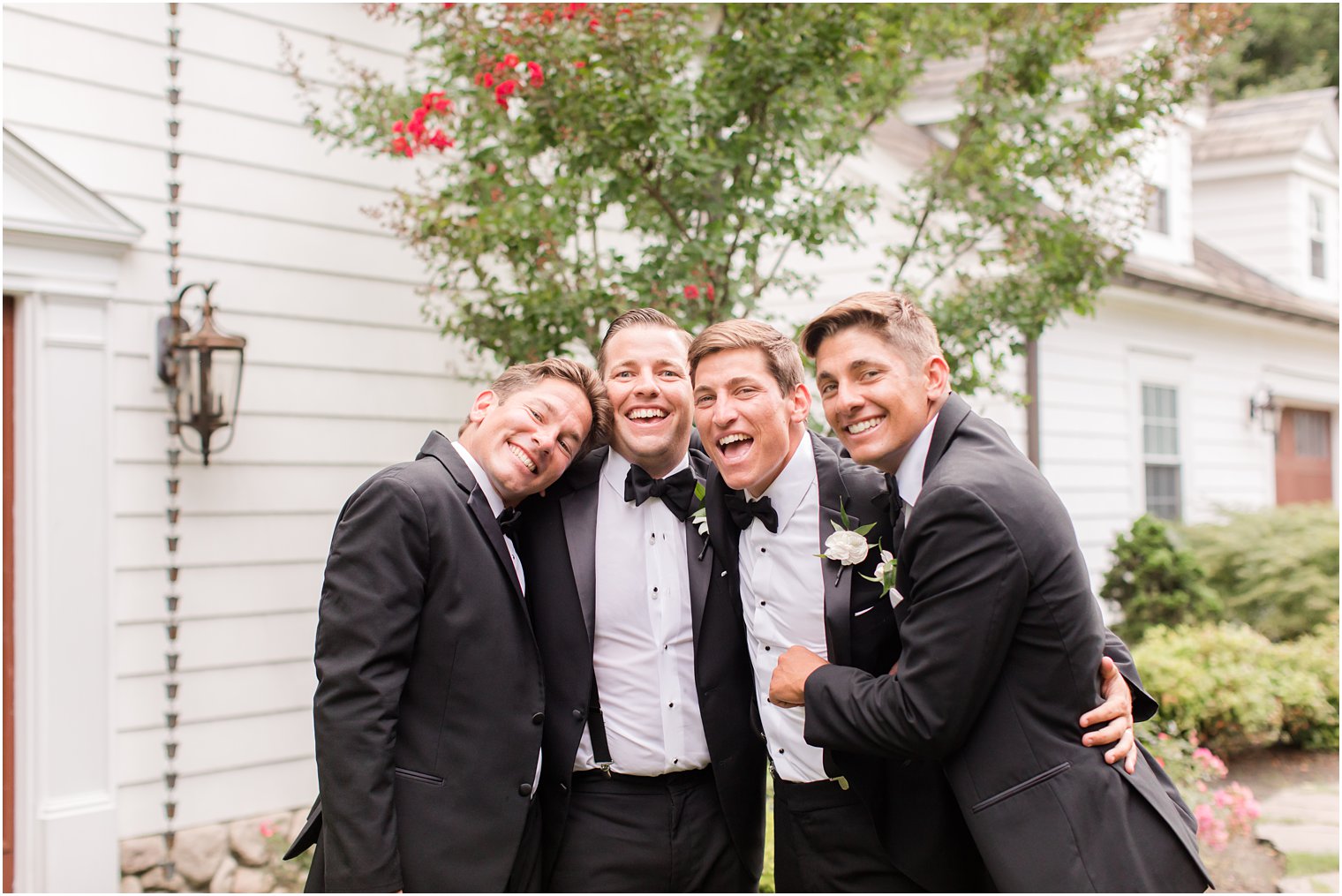 groom poses with three groomsmen laughing 