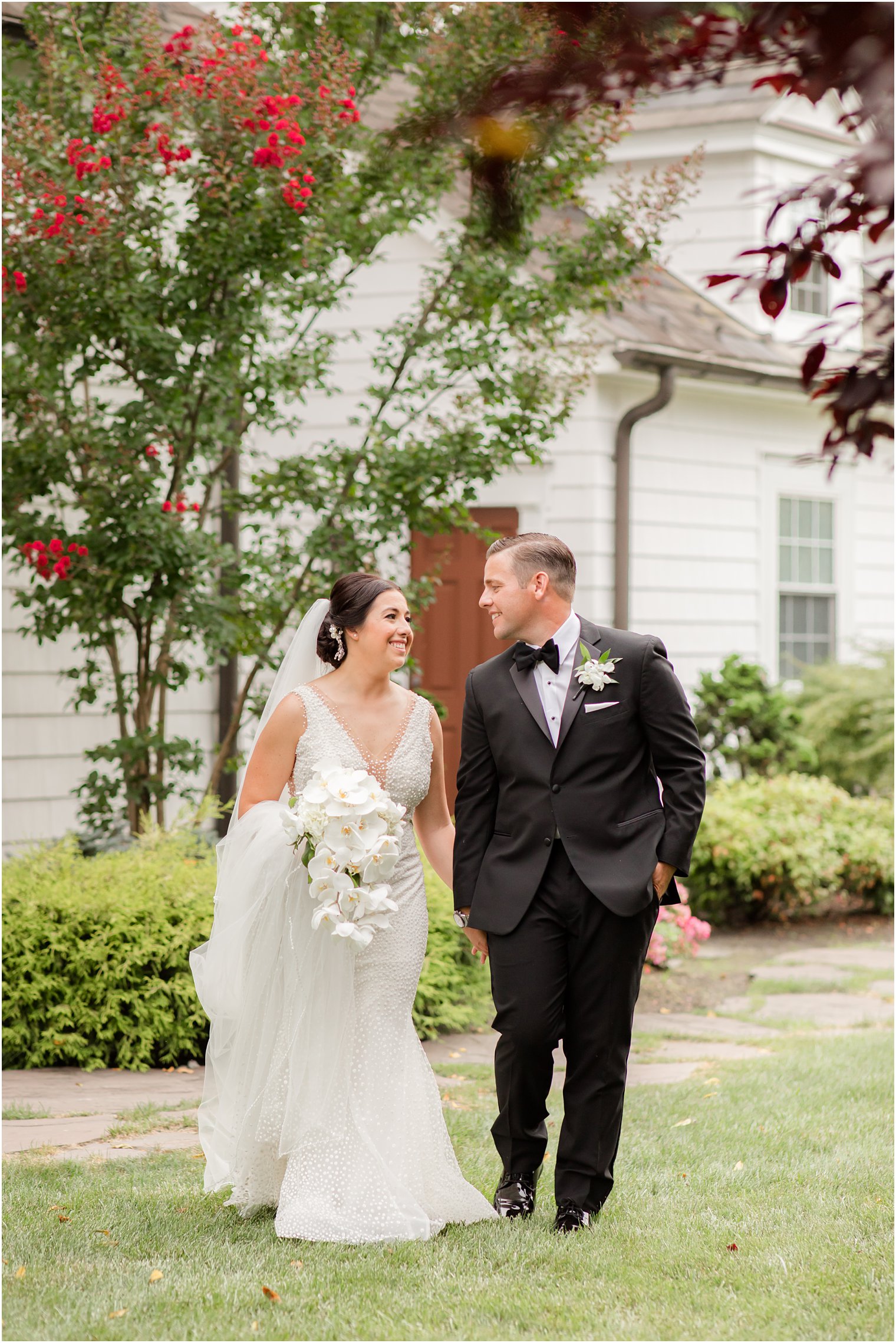 bride holding cascading bouquet of orchids walks with groom