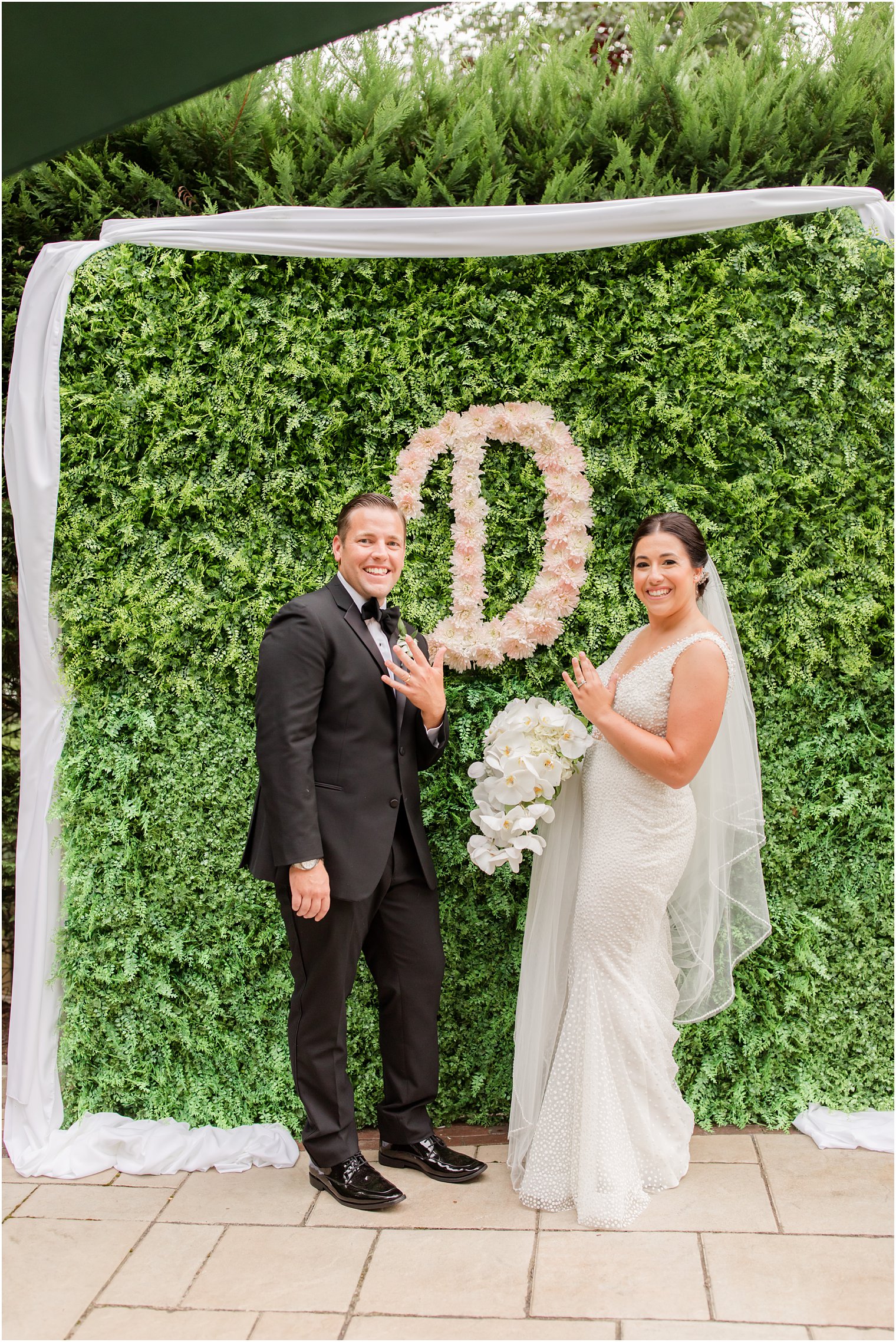 bride and groom pose with floral monogram