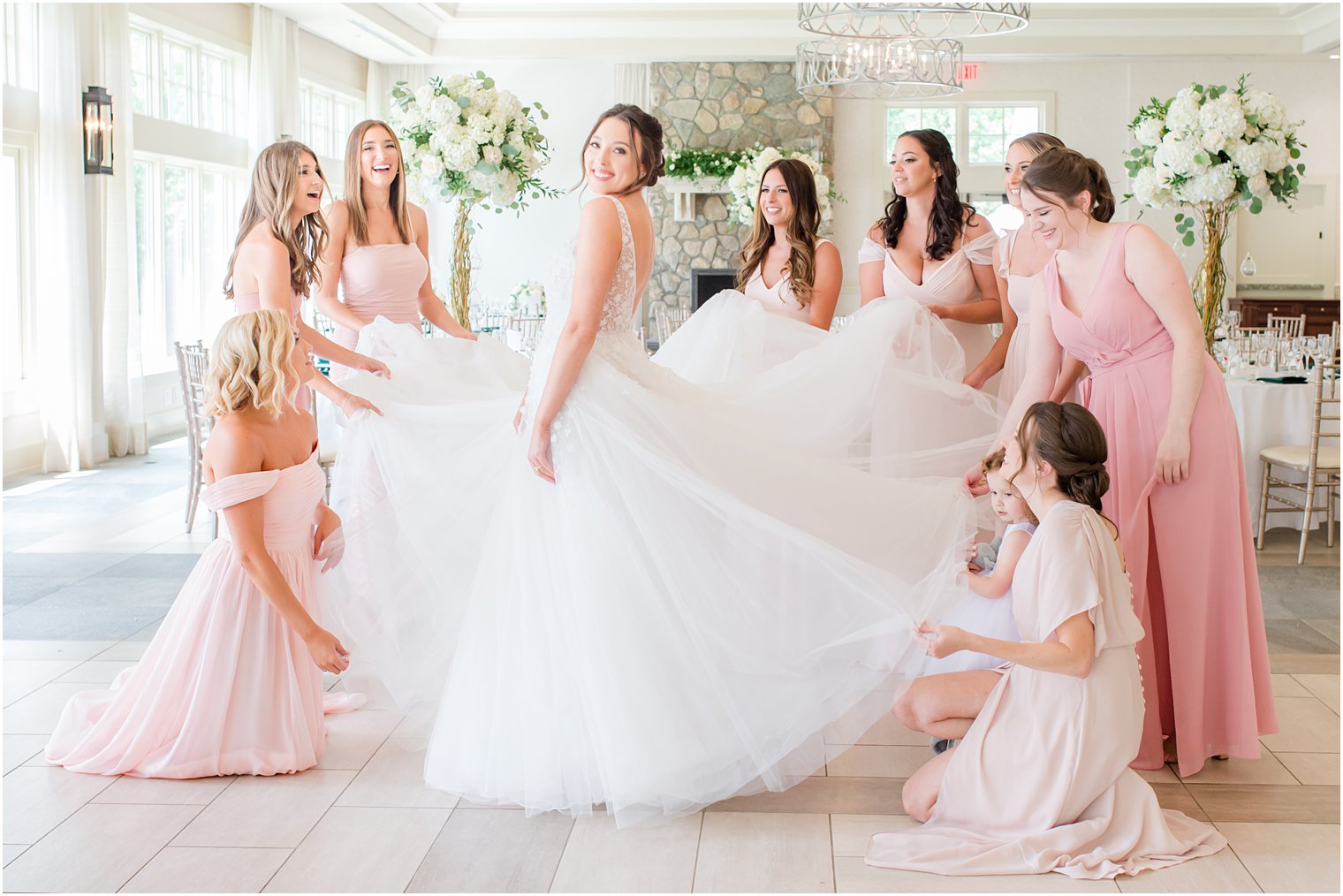 bridesmaids help bride twirl in wedding gown
